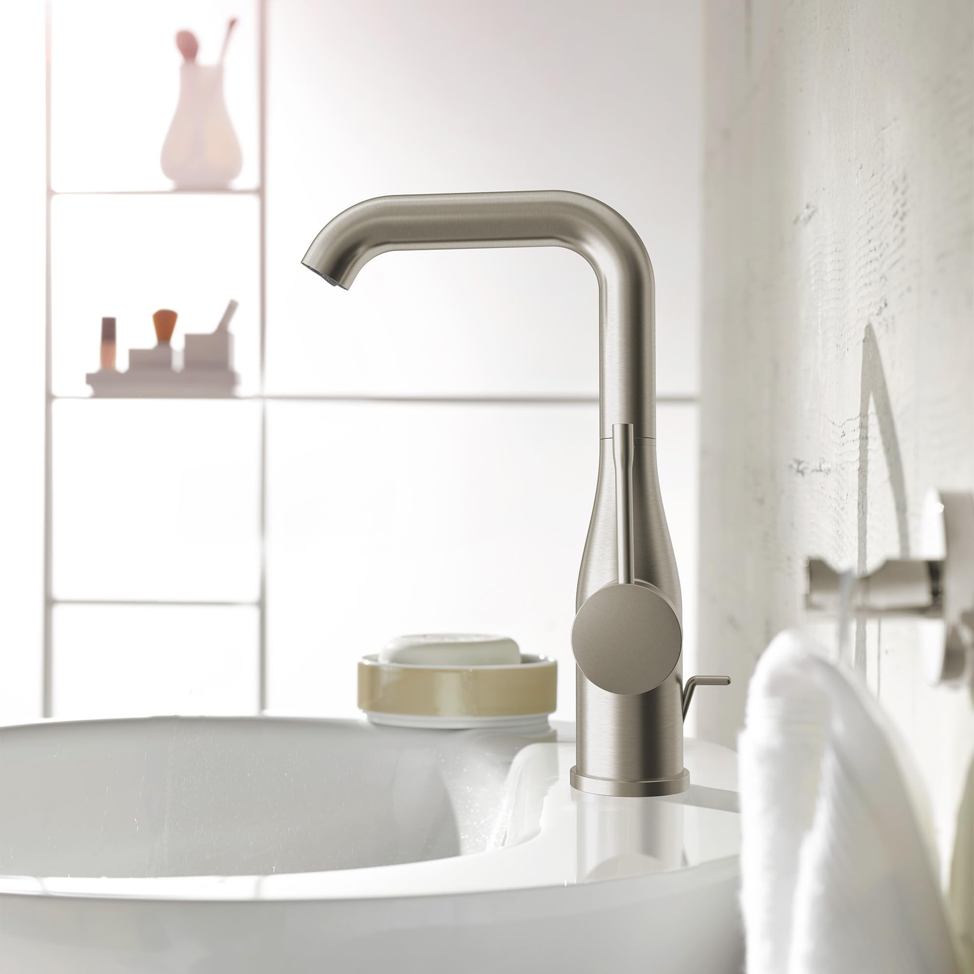Brushed nickel single-handle bathroom faucet with curved spout and round control lever mounted on white sink.