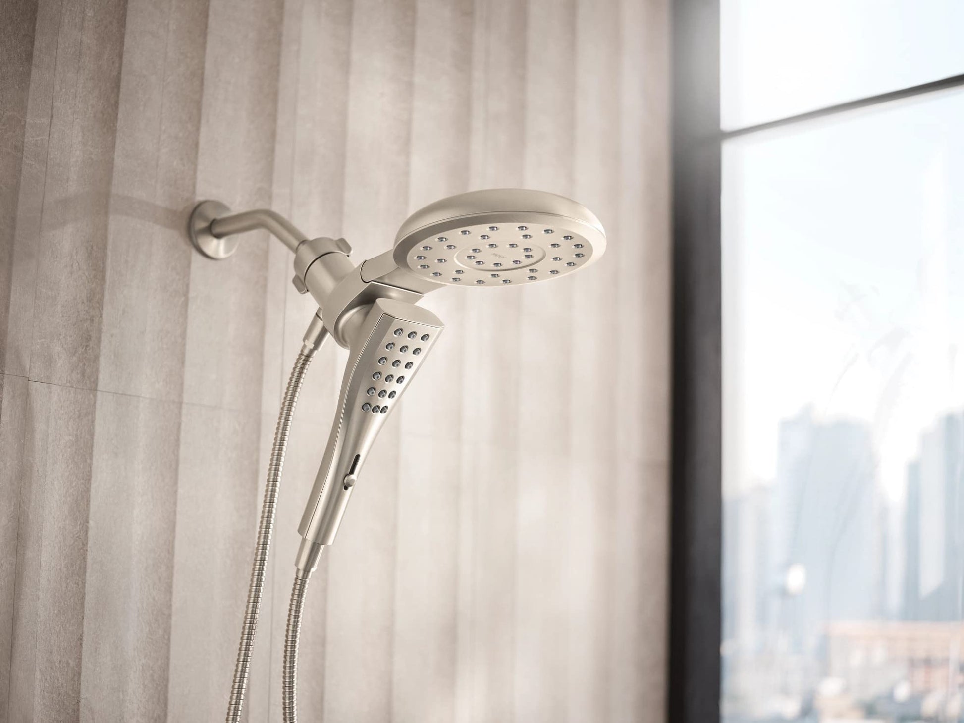 Brushed nickel round shower head with eight spray patterns and matching handheld shower connected by hose.