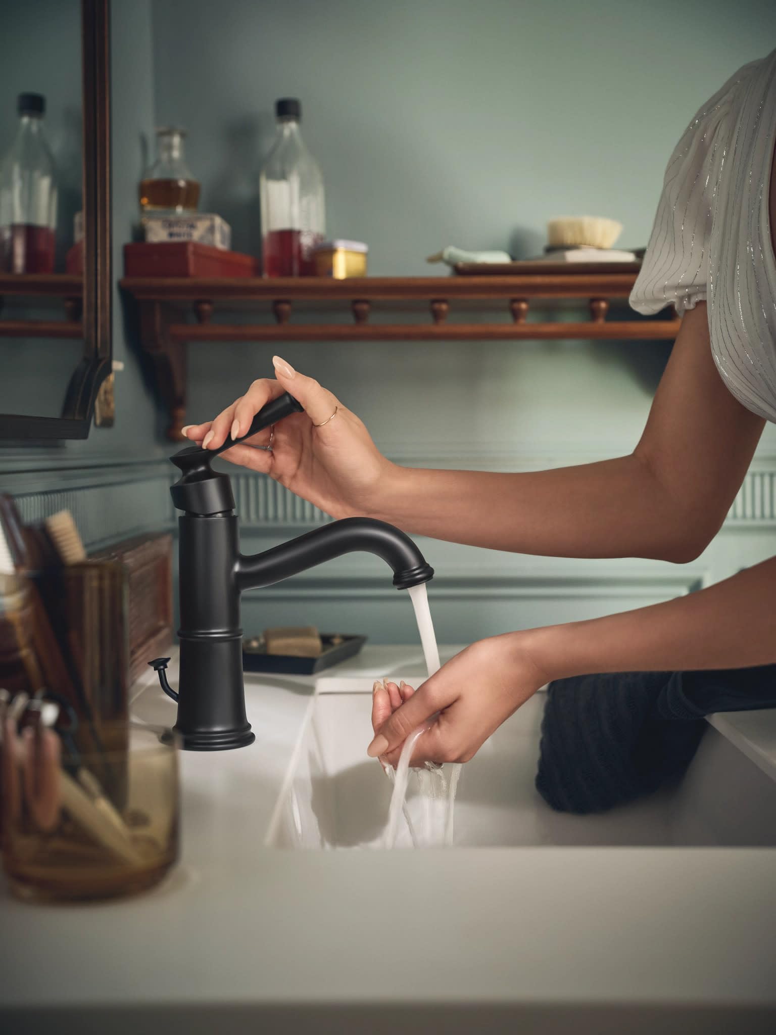 Matte black single-handle bathroom faucet with curved spout shown installed at sink with water running.