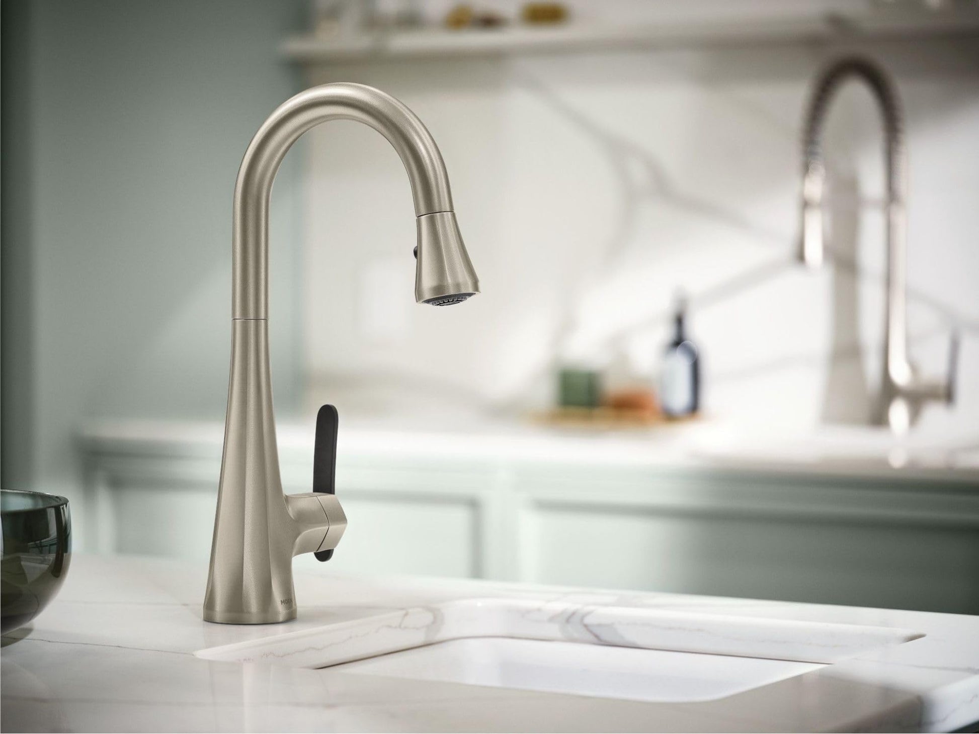 Stainless steel kitchen faucet with high arc spout and pulldown spray head mounted on white countertop.