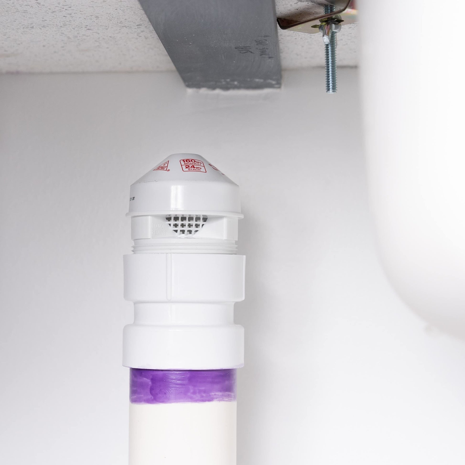 White air admittance valve with dome top and perforated vent opening, mounted on PVC adapter with purple seal visible at base