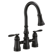 Matte black two-handle bridge kitchen faucet with curved pulldown spout and lever handles.