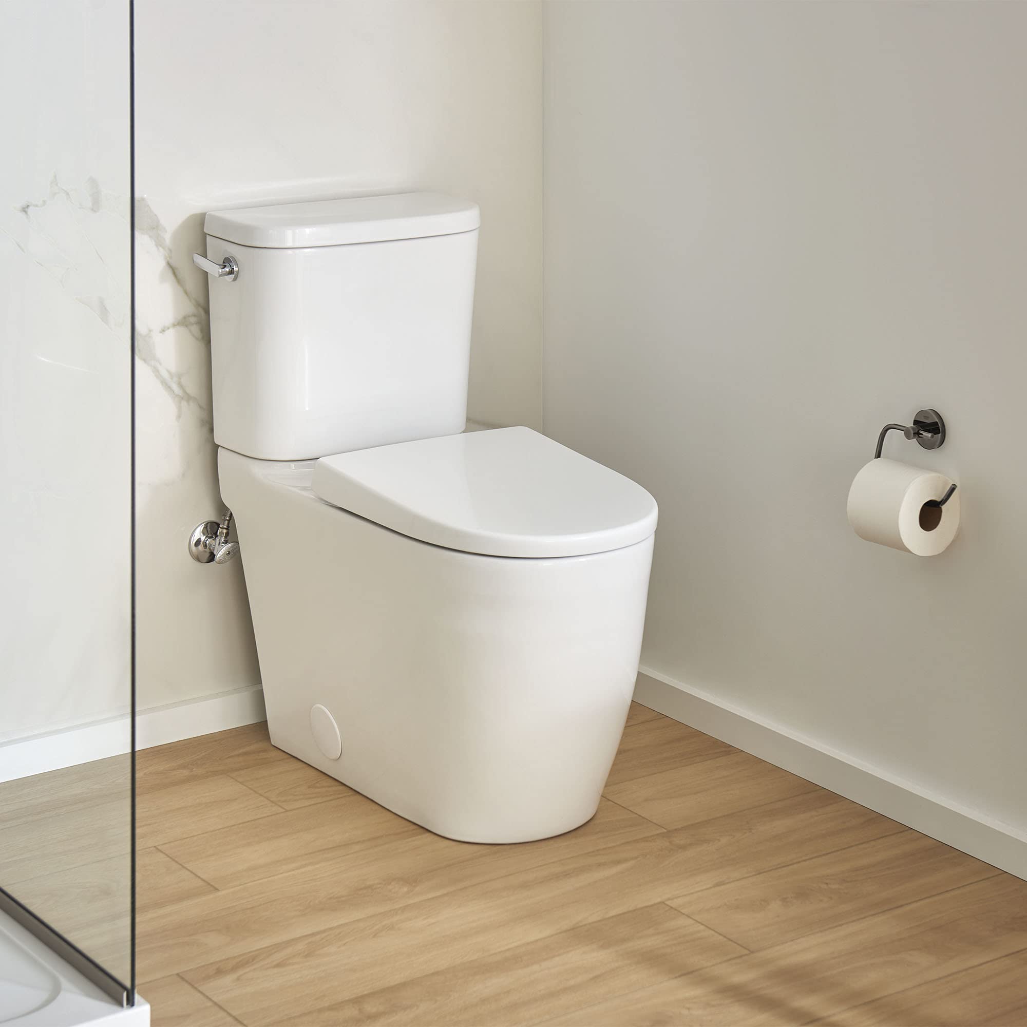 White elongated two-piece toilet with matching seat and tank in a bathroom setting.