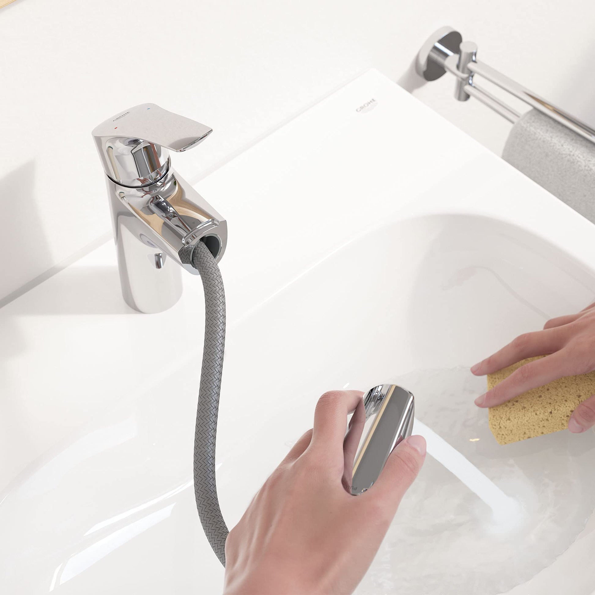 Chrome single-handle bathroom faucet with pull-out spray hose installed on white sink basin.