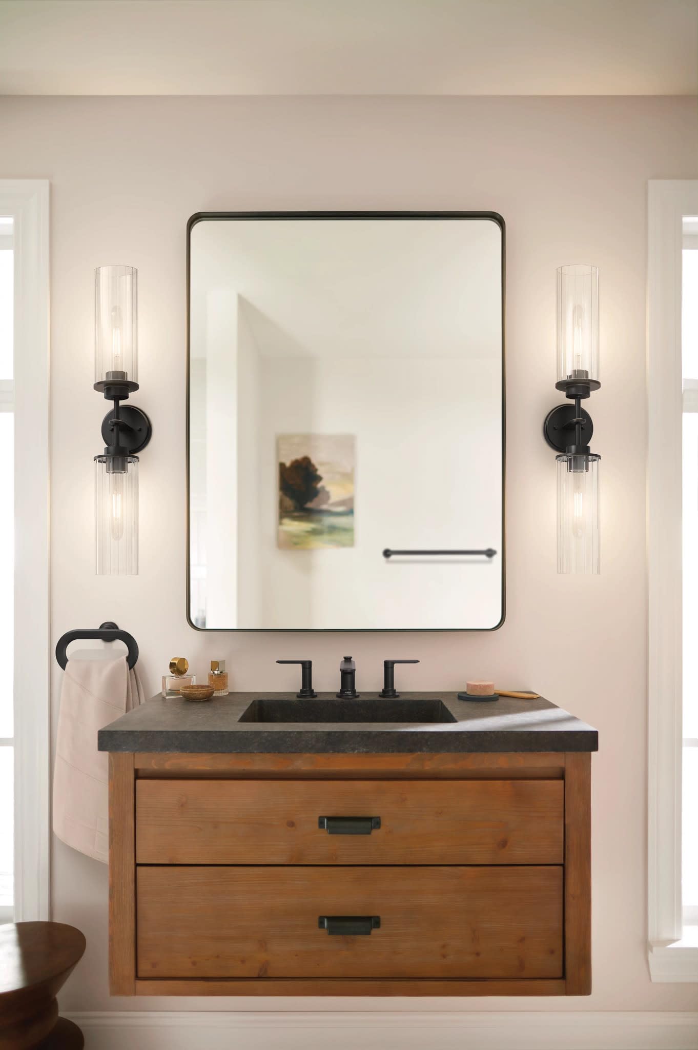 Matte black two-handle widespread bathroom sink faucet mounted on dark countertop above wooden vanity.