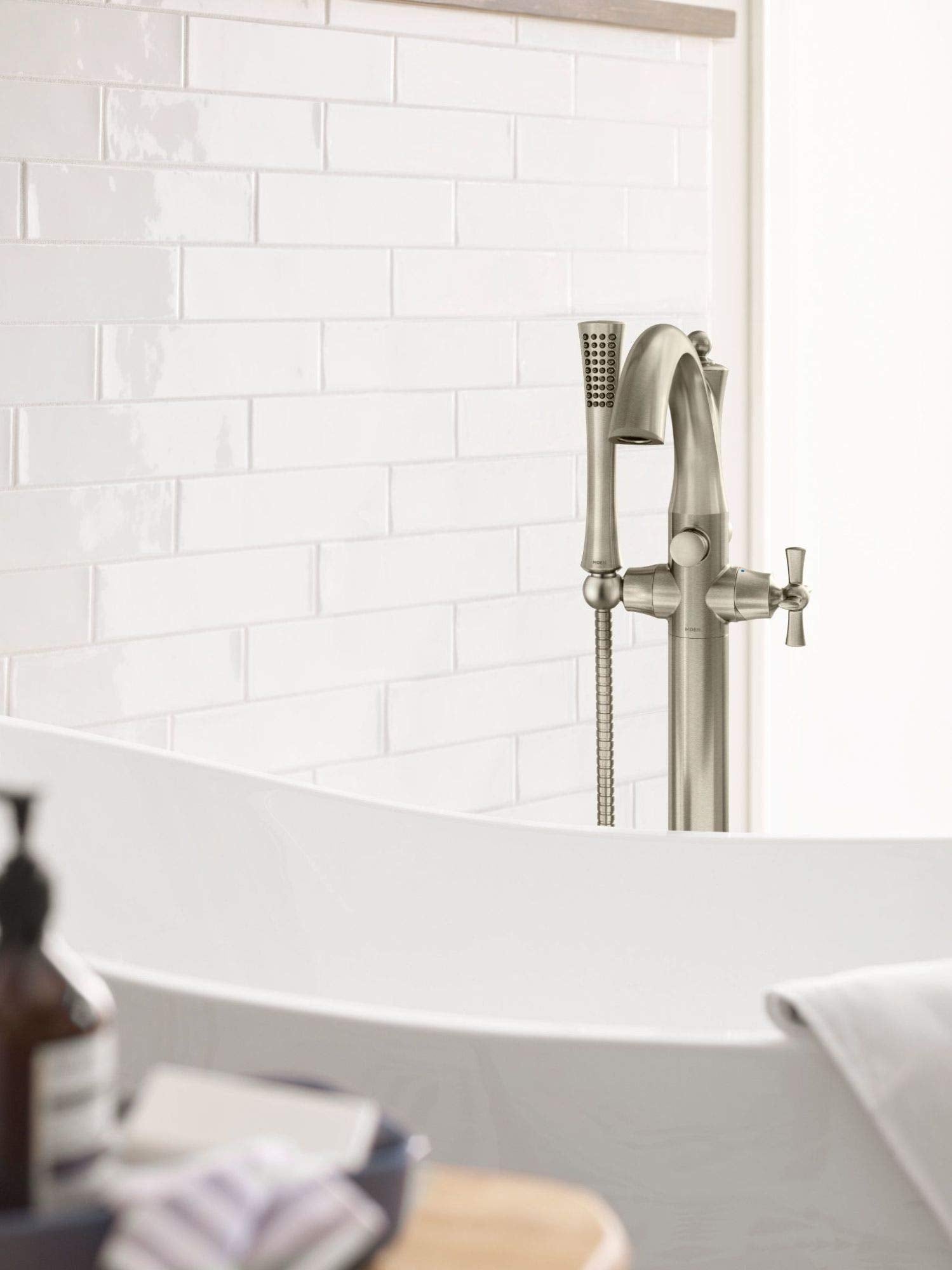 Chrome freestanding tub filler with single handle, curved spout, and detachable handheld showerhead on hose.