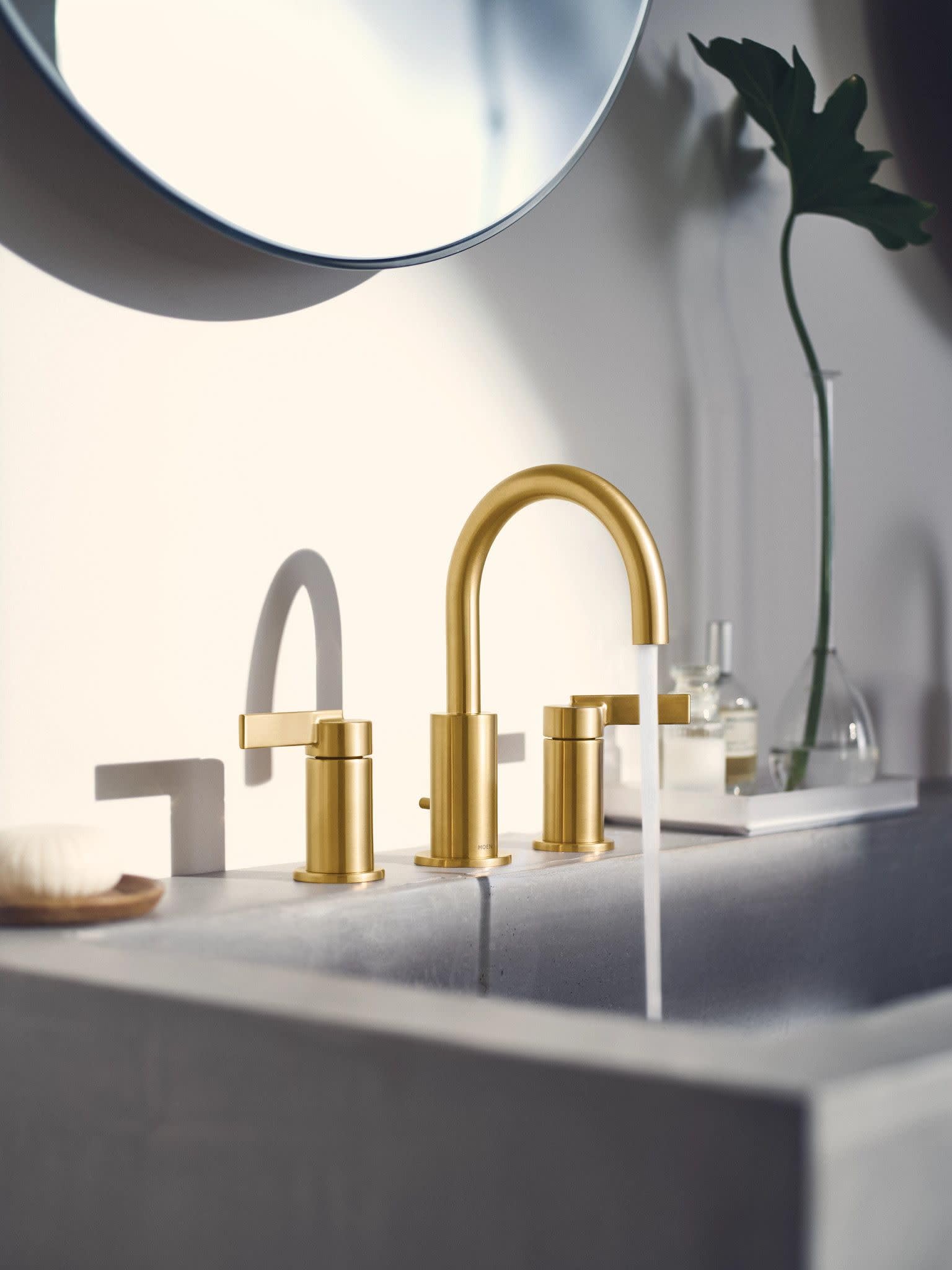 Brushed gold widespread bathroom faucet with high arc spout and two handles installed on white sink counter.