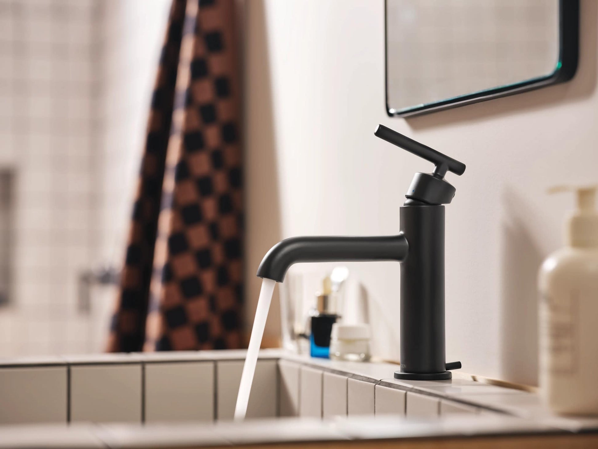 Matte black single-handle bathroom faucet with curved spout and lever handle installed on sink deck.