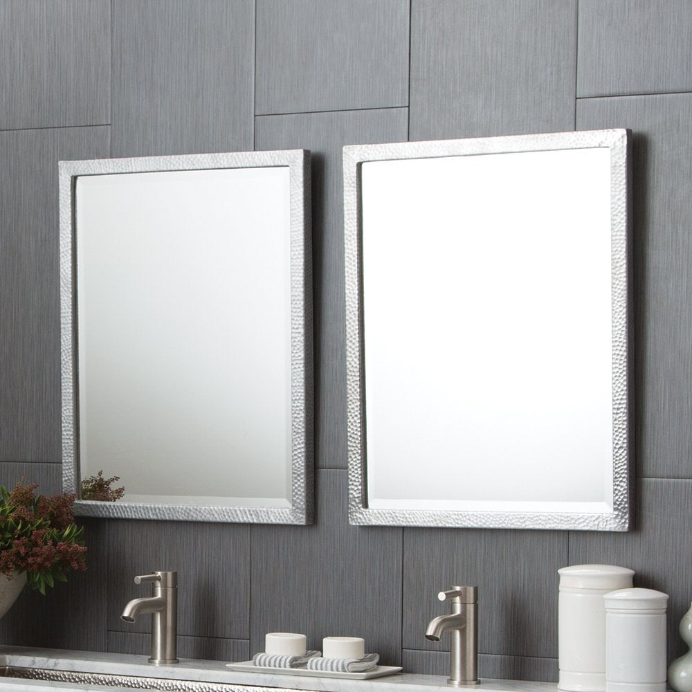 Two rectangular mirrors with white textured frames mounted on gray tile wall above bathroom vanity with faucets and accessori