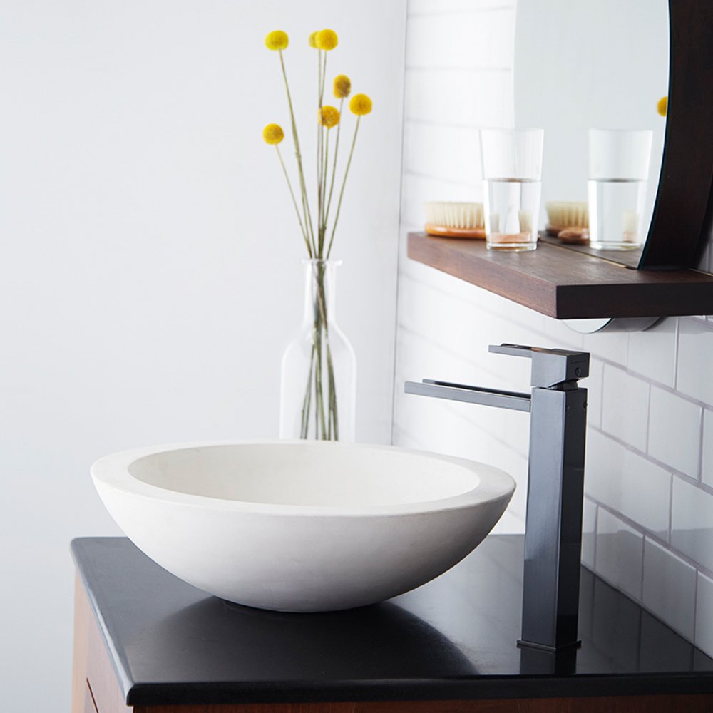 Pearl white ceramic round vessel sink with curved bowl shape on dark countertop.