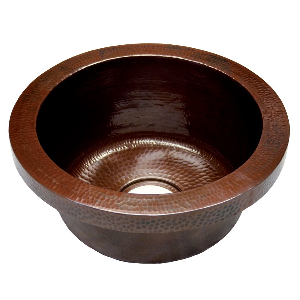 Antique copper round bar sink with hammered texture and dark interior basin.