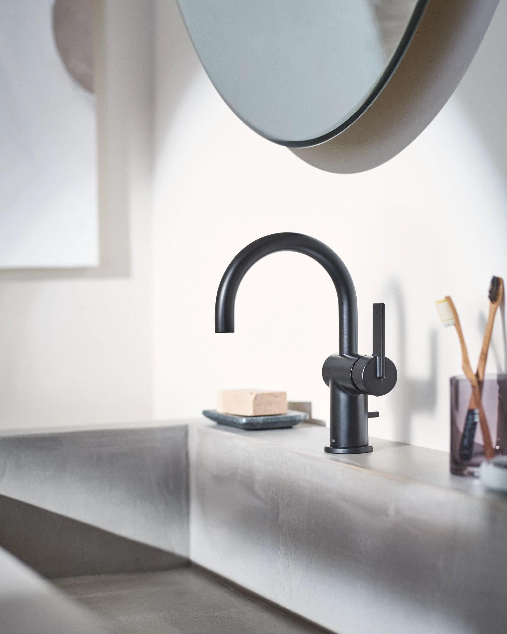 Matte black single-handle bathroom faucet with curved spout mounted on white sink counter.