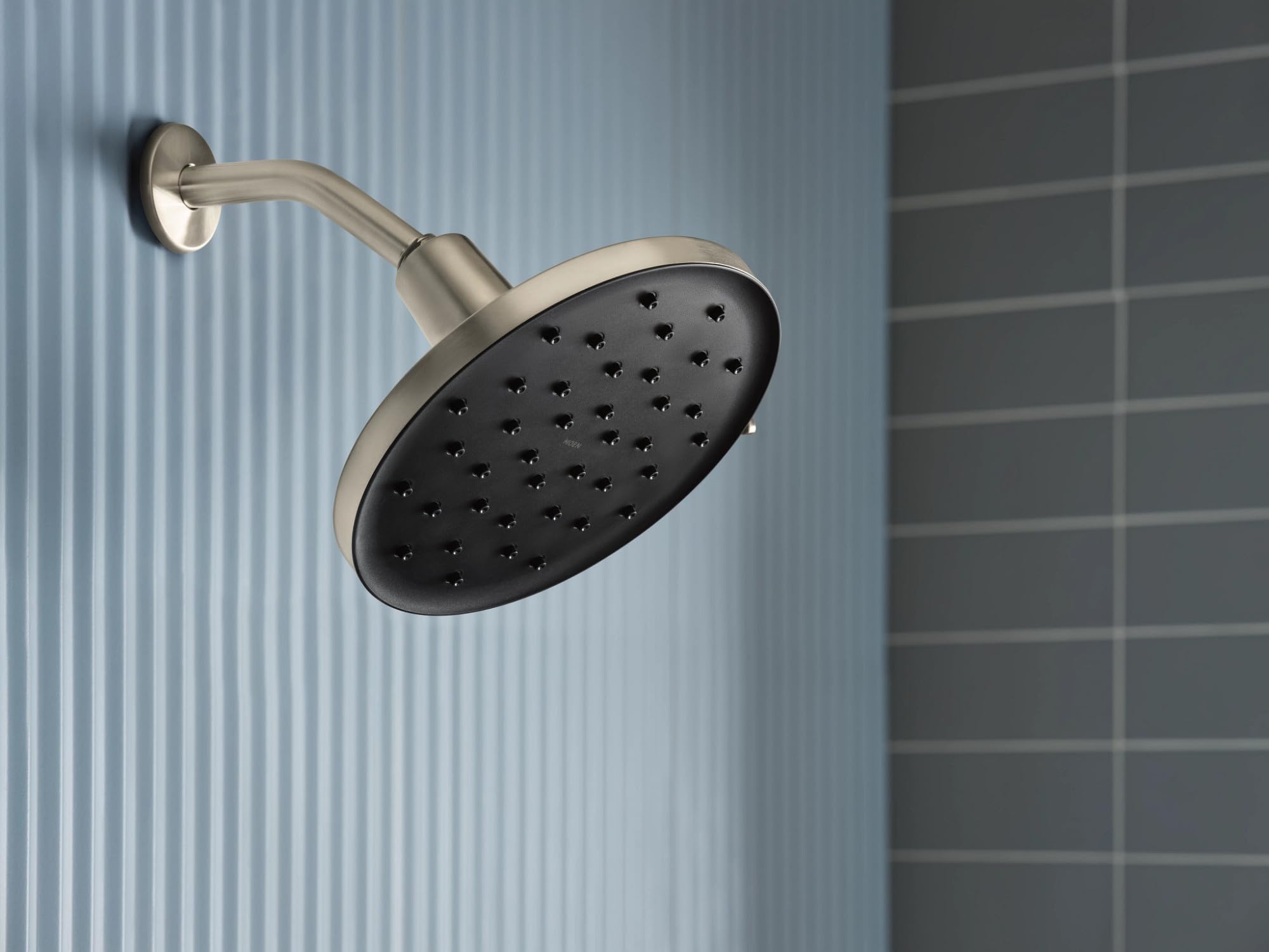 Brushed nickel rainshower head with curved arm and multiple spray jets mounted on bathroom wall.