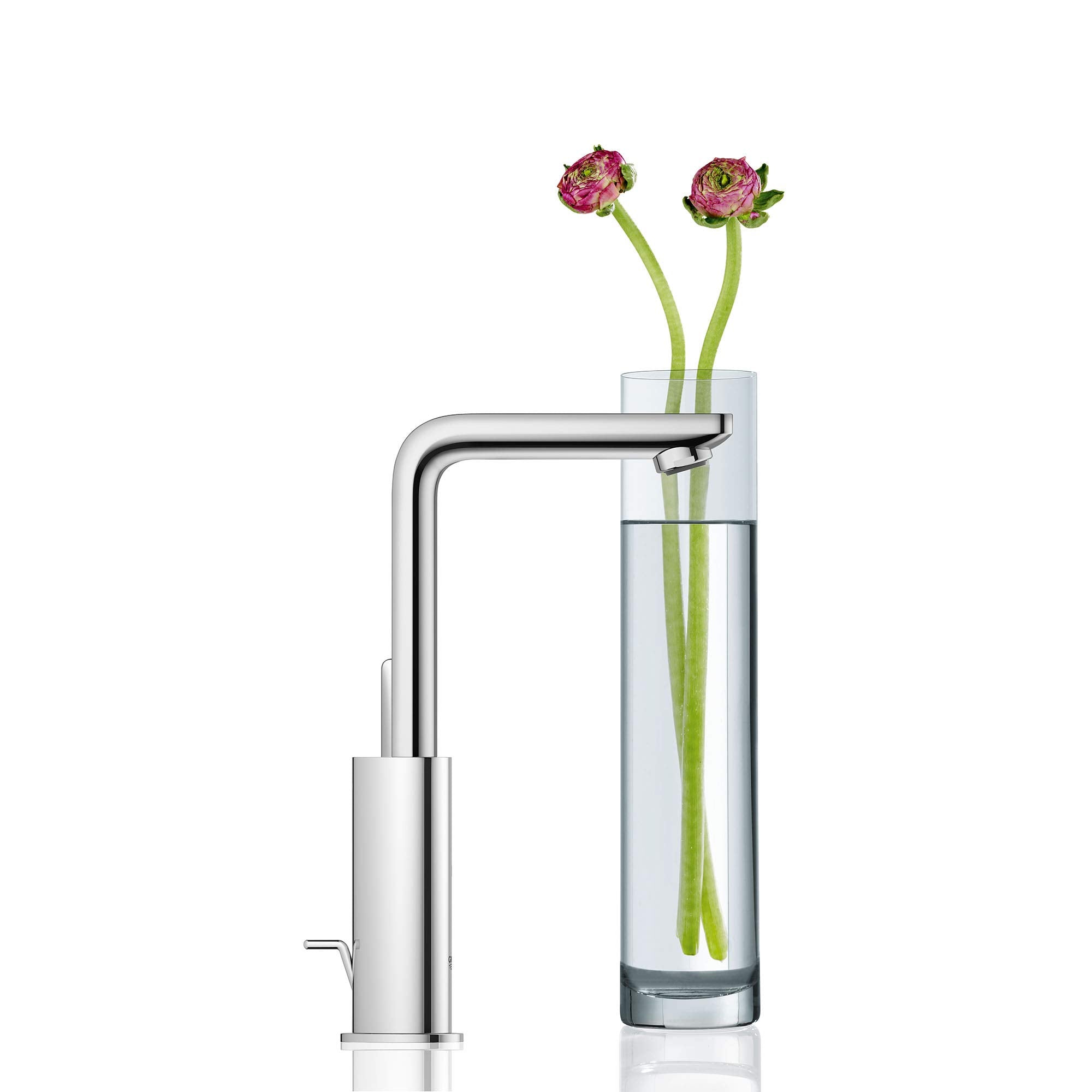 Chrome single-handle bathroom faucet with angular spout and rounded base next to glass vase with pink flowers.