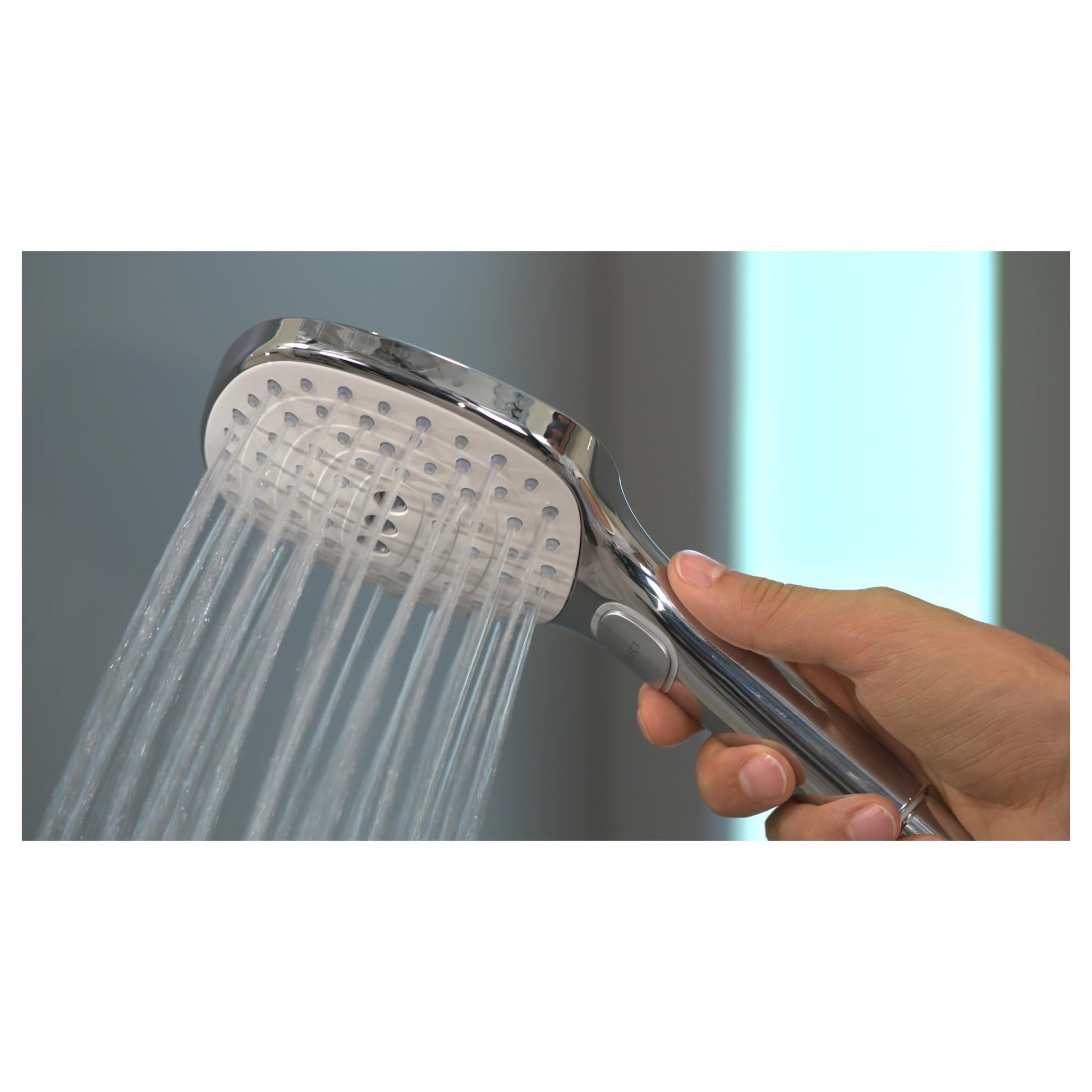 White and chrome handheld showerhead with multiple spray jets being held in a hand with water flowing.