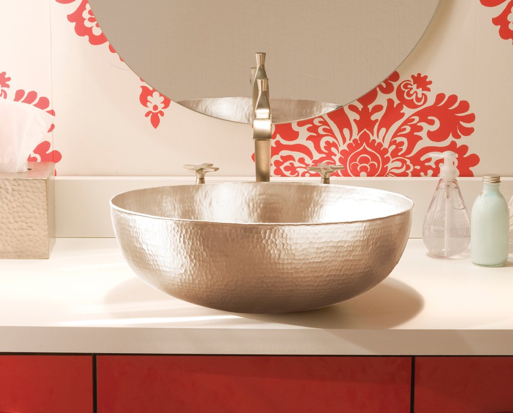 Round hammered copper vessel sink with brushed nickel faucet on white countertop.