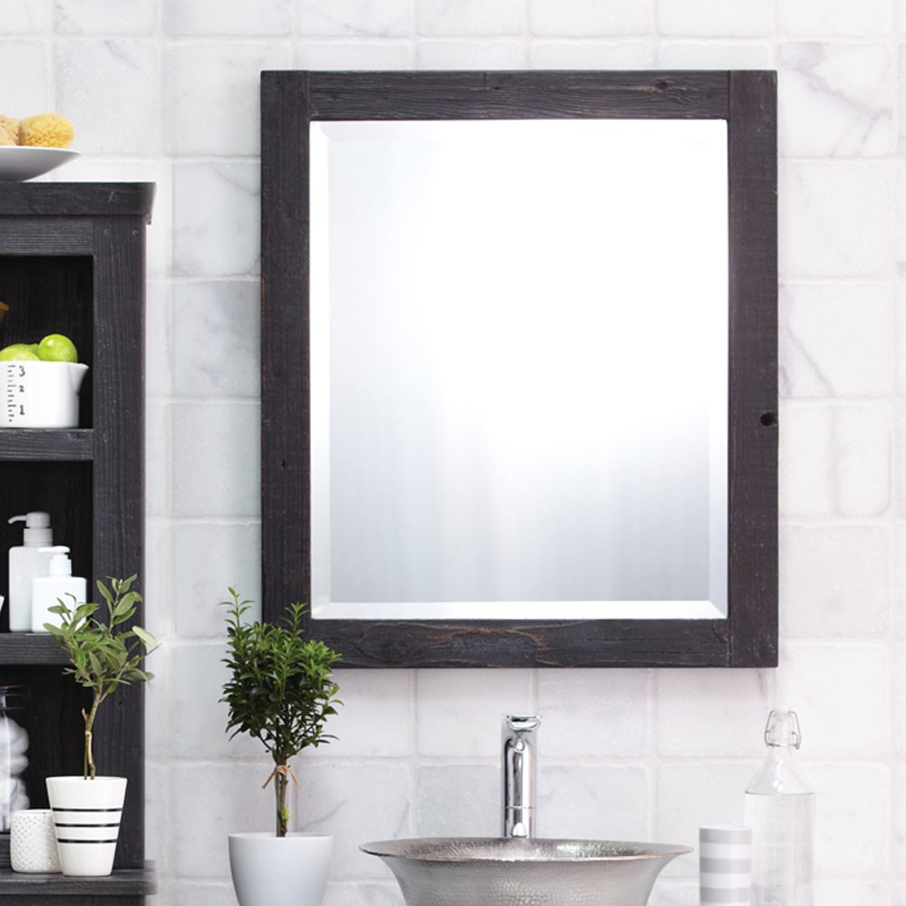 Large rectangular mirror with dark wood frame mounted above bathroom sink with white subway tile backsplash.