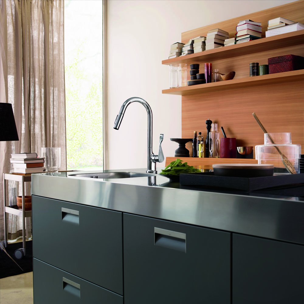 Chrome high arc kitchen faucet with pull-down spray mounted on stainless steel sink in dark cabinetry.