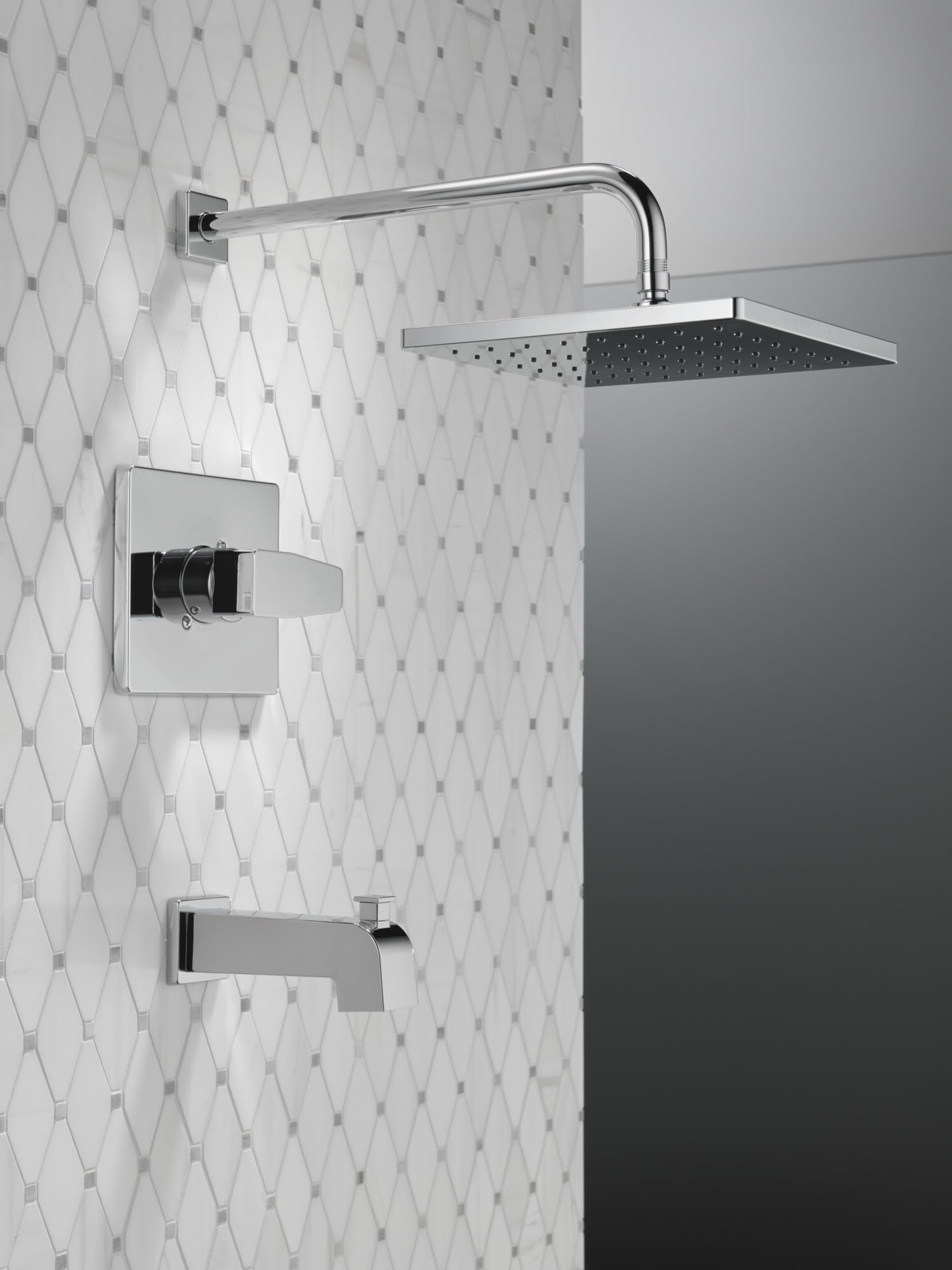 Chrome tub and shower trim with square showerhead, lever handle, and tub spout mounted on white tile wall.