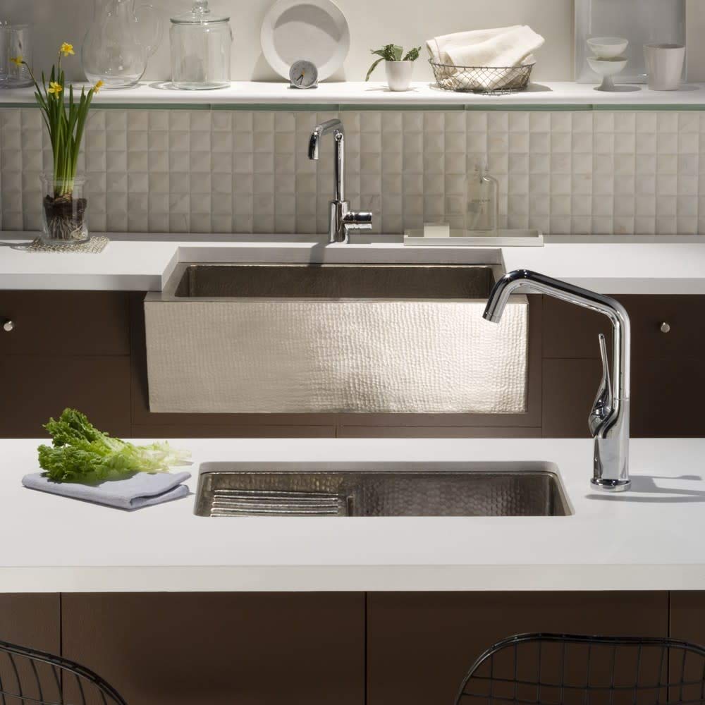 Hammered copper undermount bar sink with antique finish installed in kitchen countertop next to prep sink.