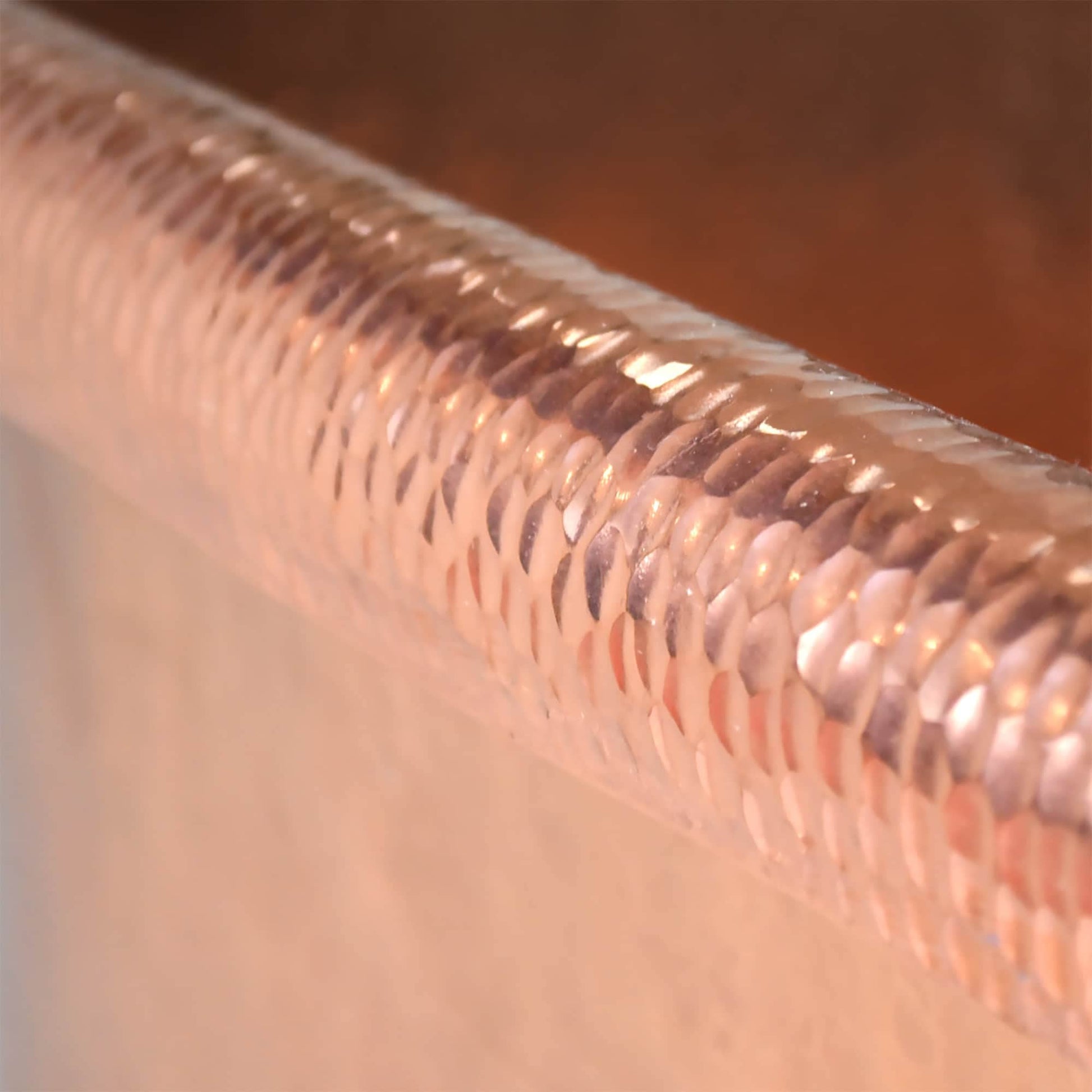 Antique copper bathtub rim with hammered texture detail and patina finish.