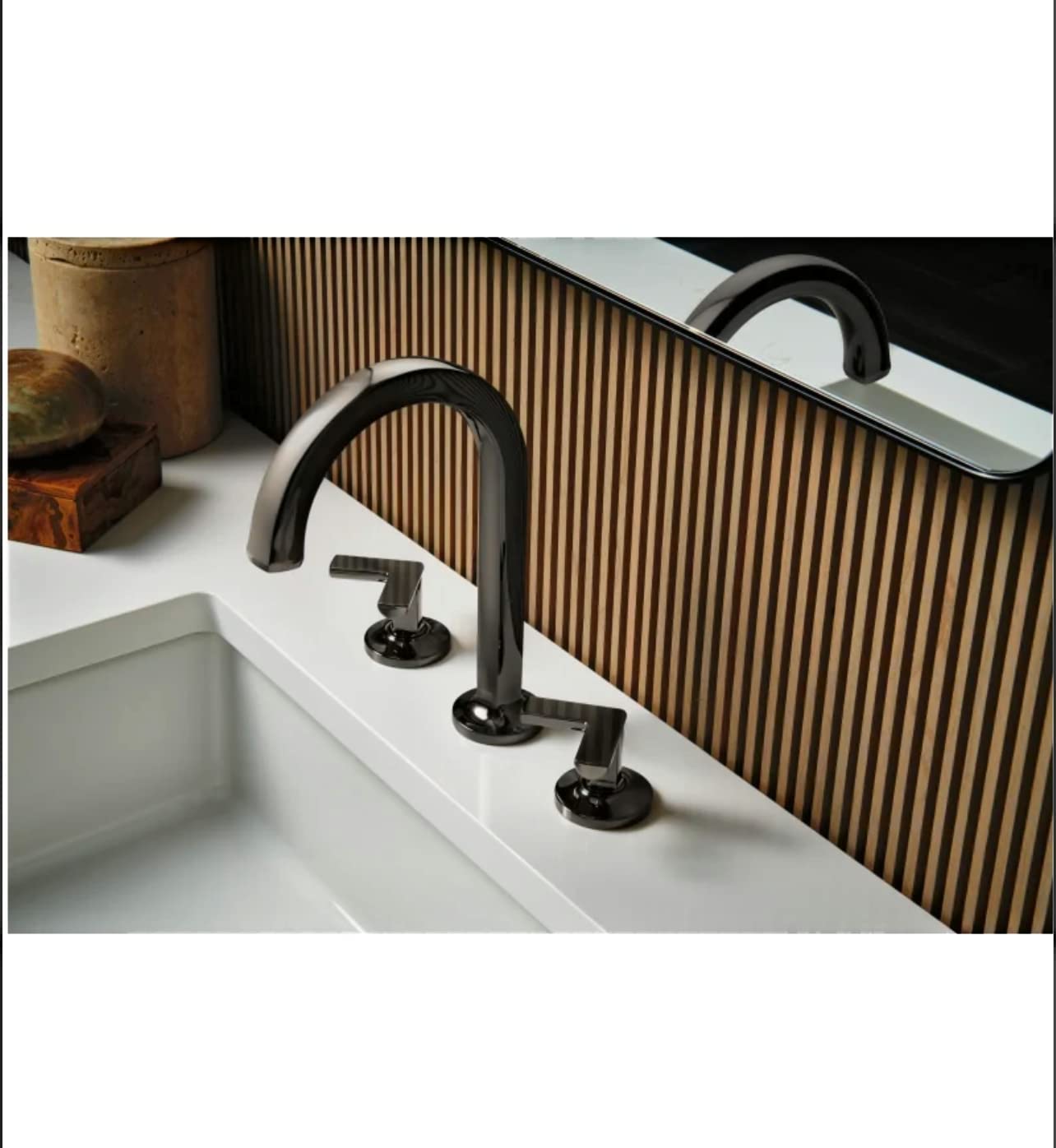Black widespread lavatory faucet with curved cross handles installed on white sink countertop.