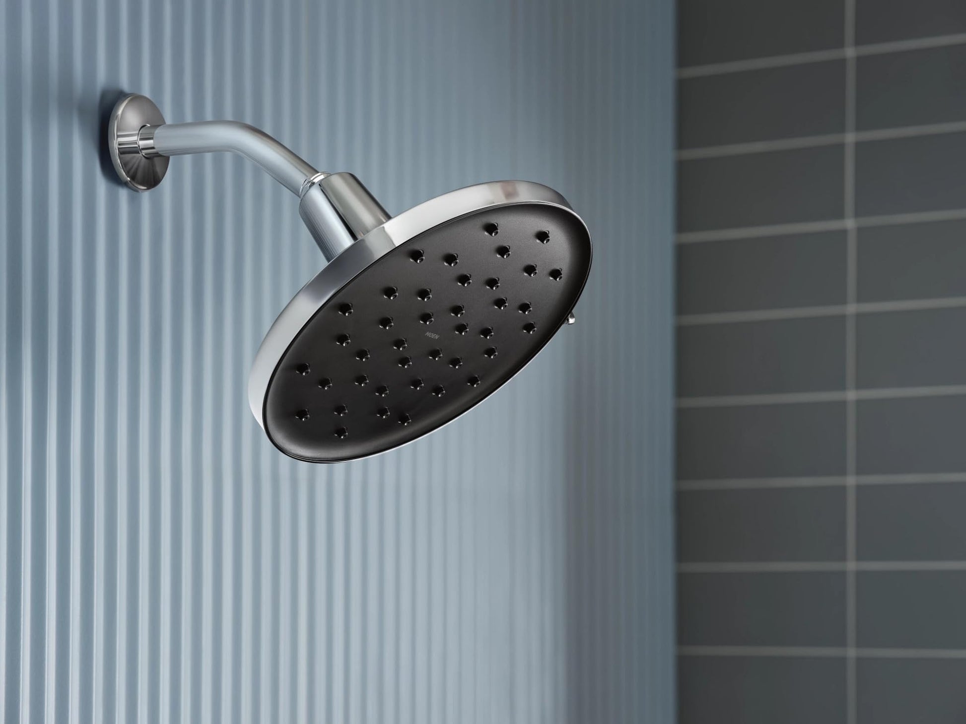 Chrome rainshower head with adjustable arm mounted on bathroom wall tile.