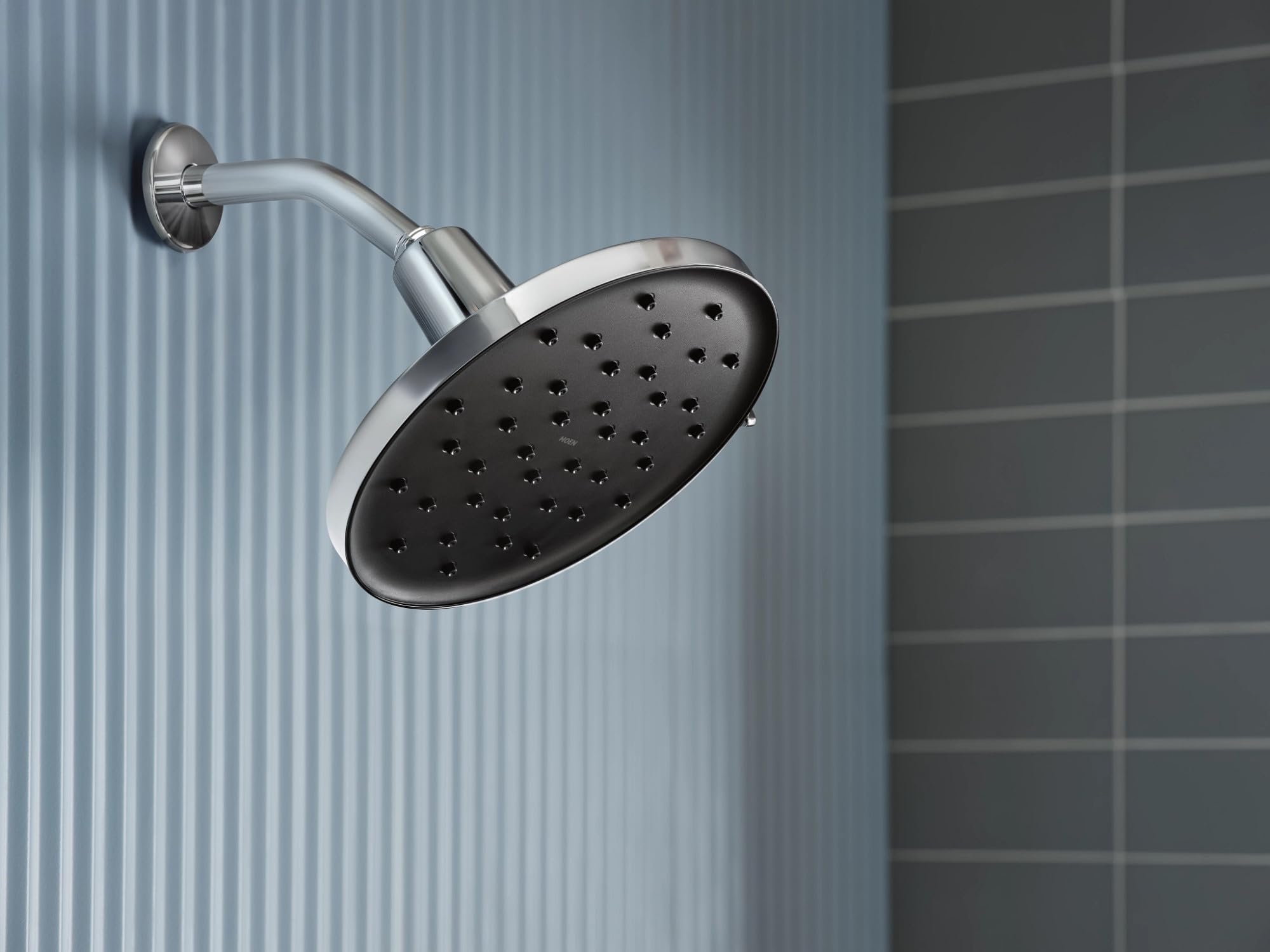 Chrome rainshower head with adjustable arm mounted on bathroom wall tile.