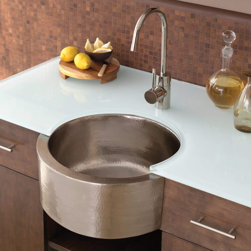 Hammered copper undermount bar sink with textured finish installed in white countertop with chrome faucet.