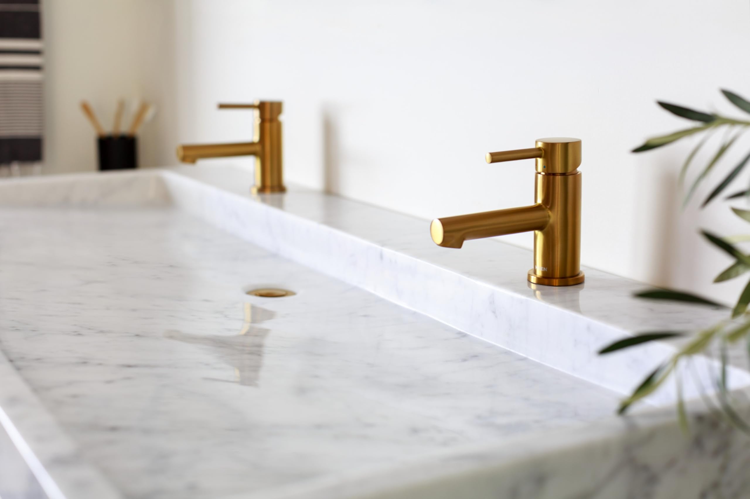 Brushed nickel single-handle bathroom faucet with low arc spout installed on marble countertop.
