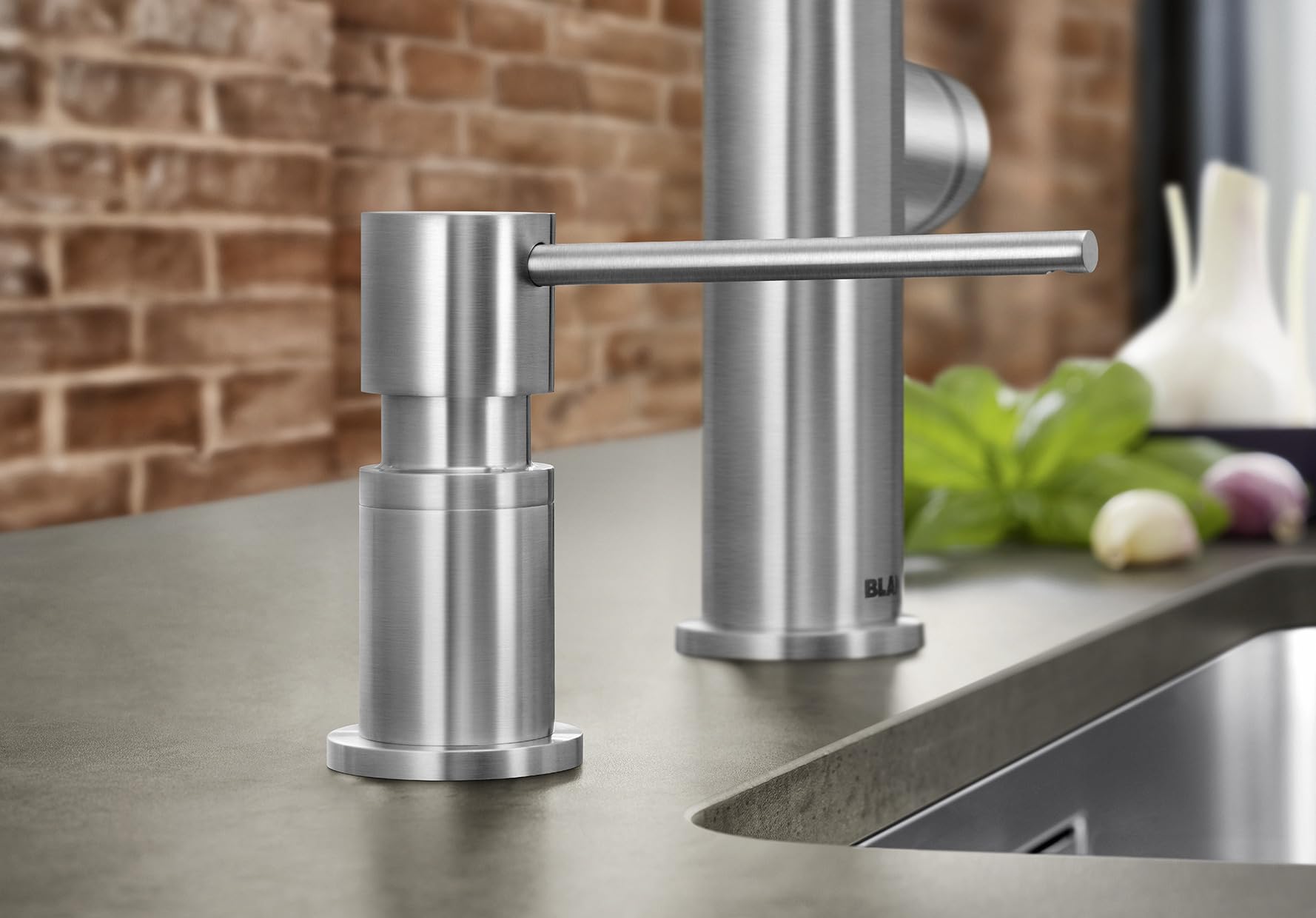 Satin dark steel soap dispenser with cylindrical pump and horizontal lever spout mounted on kitchen countertop.