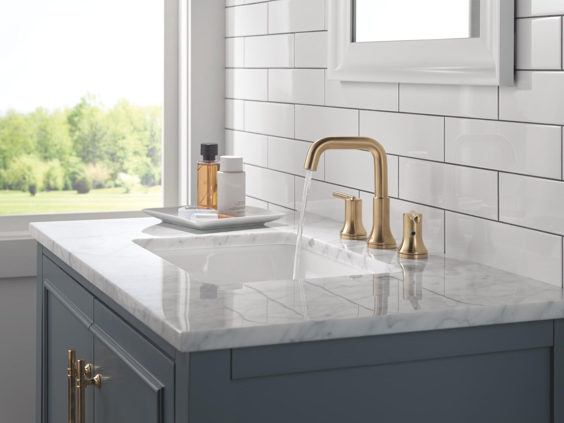 Champagne bronze two-handle widespread bathroom faucet with curved spout installed on marble countertop sink.