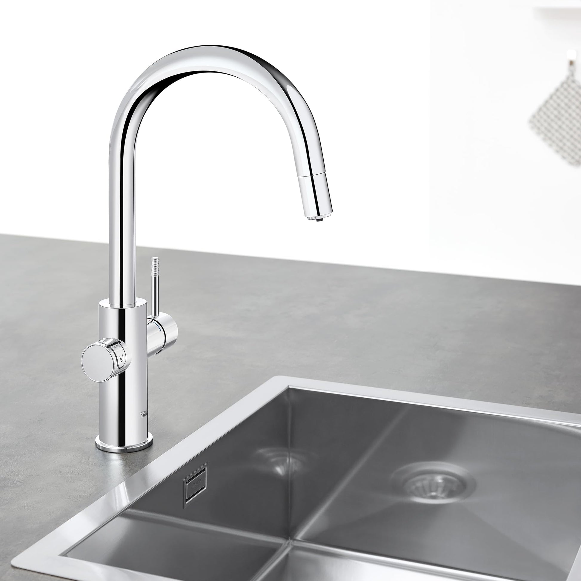 Chrome pull-down kitchen faucet with curved spout and dual circular handles mounted above stainless steel sink.