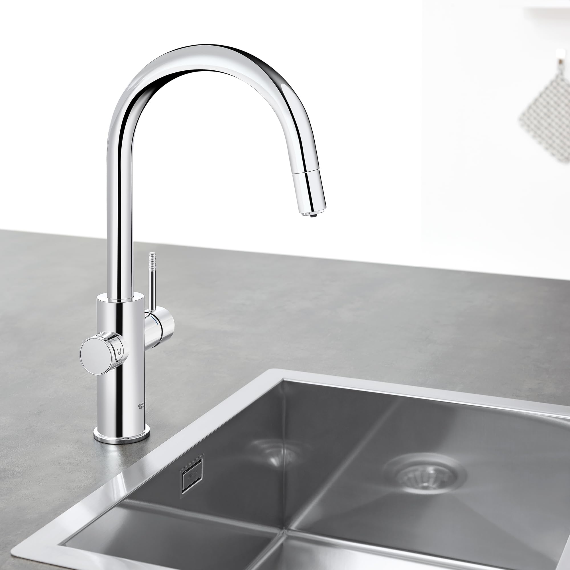 Chrome pull-down kitchen faucet with curved spout and dual circular handles mounted above stainless steel sink.