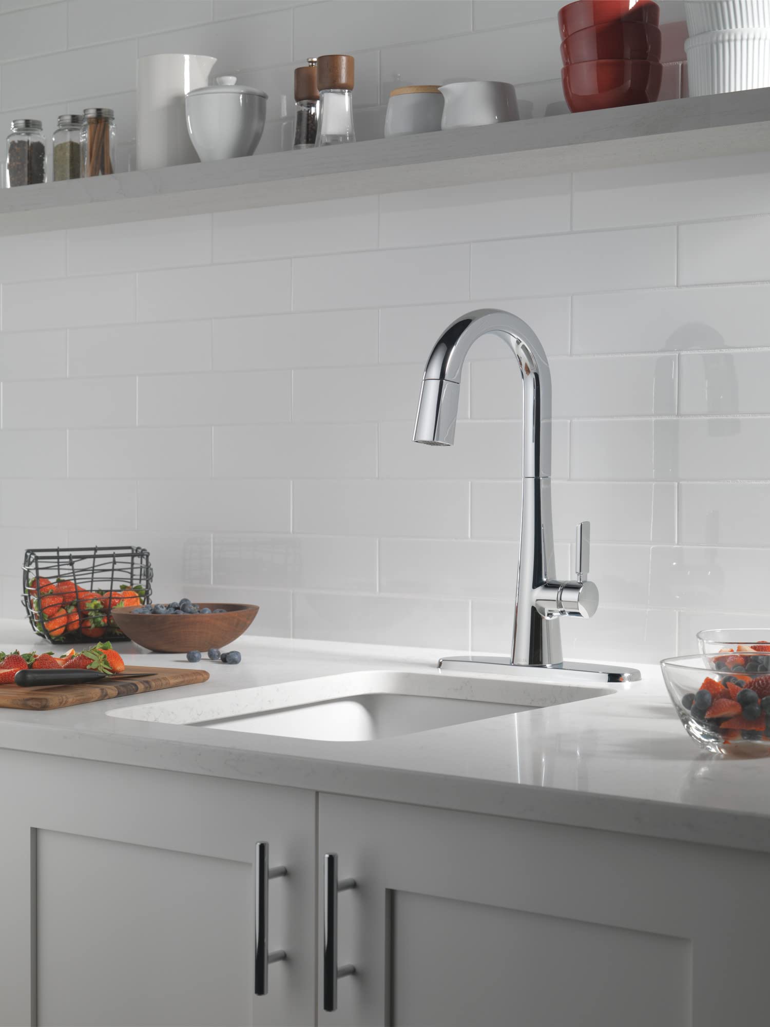 Chrome pull-down kitchen faucet with single lever handle mounted above white rectangular sink in modern kitchen.