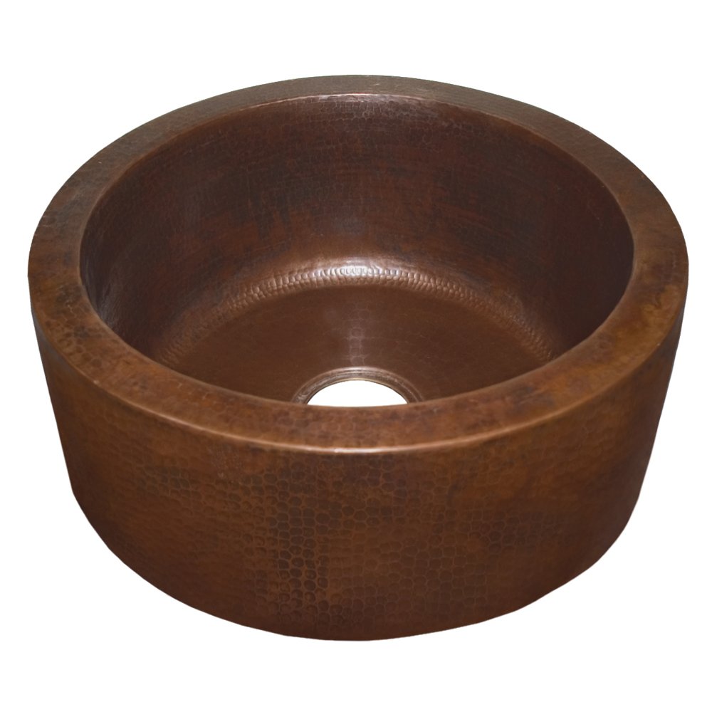 Round hammered copper undermount sink with textured finish and single drain opening.