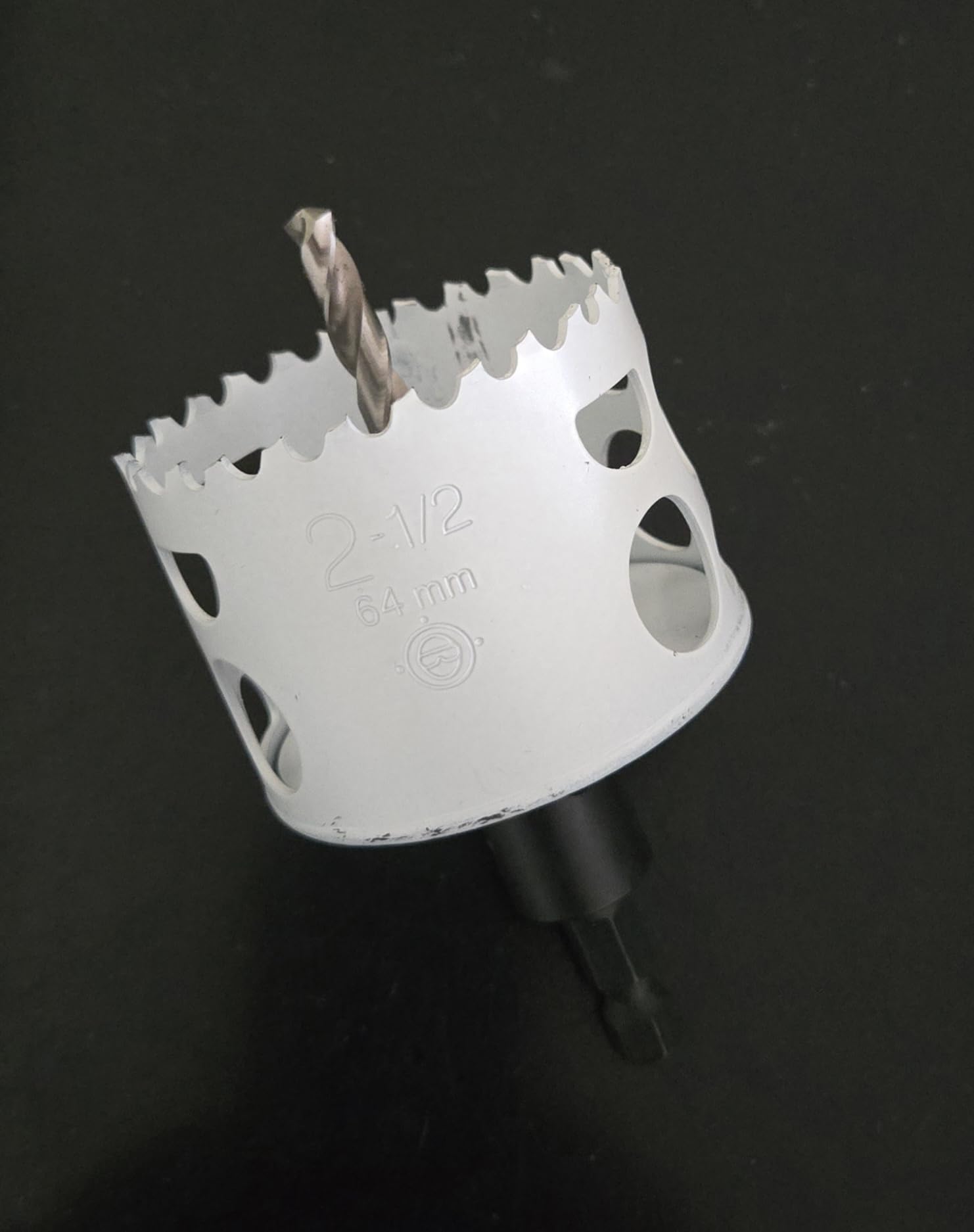 White bi-metal hole saw with serrated cutting edge and twist drill arbor, marked 2-1/2" and 64mm.