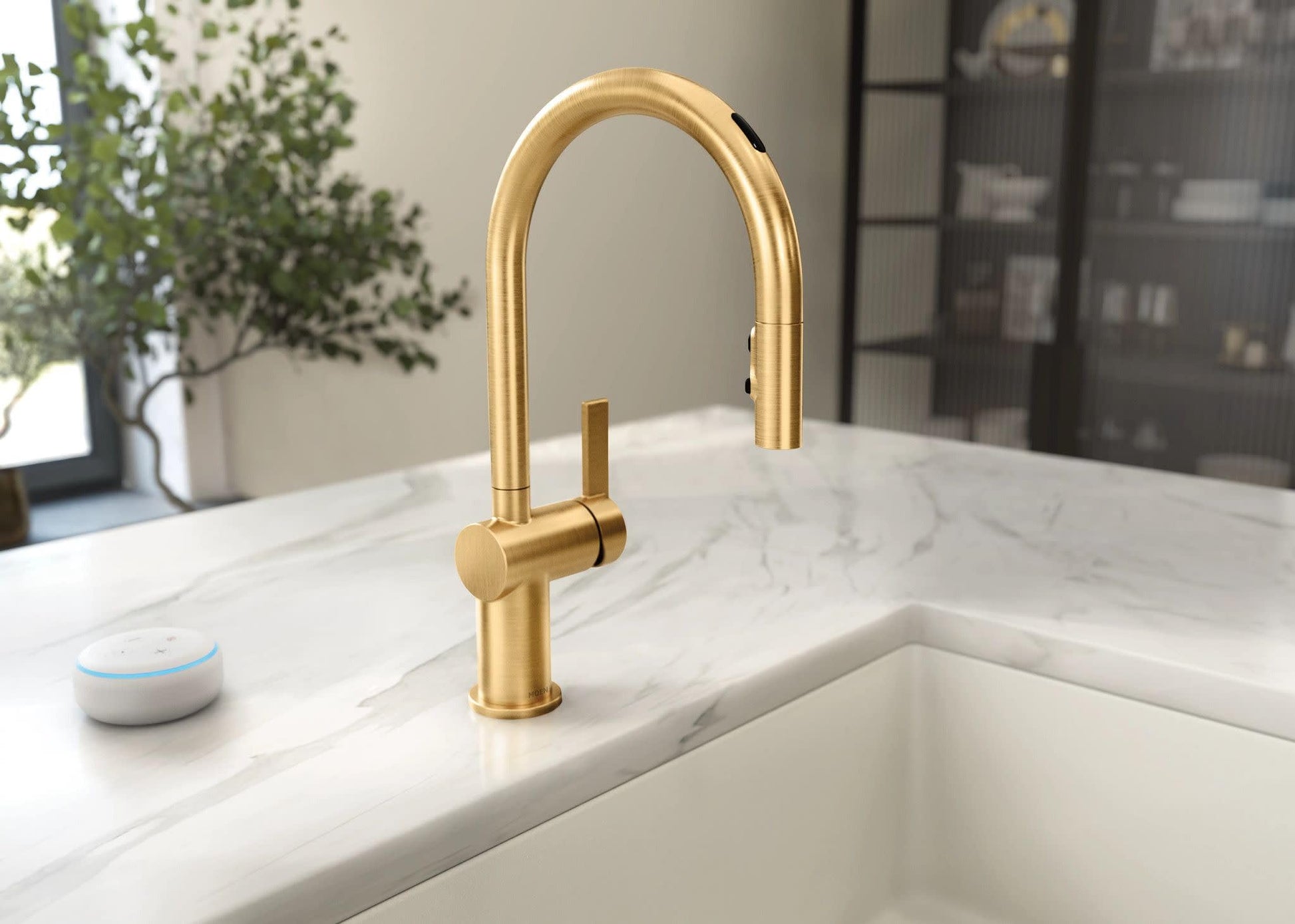 Brushed gold pulldown kitchen faucet with single handle and curved spout installed on white marble countertop above sink.