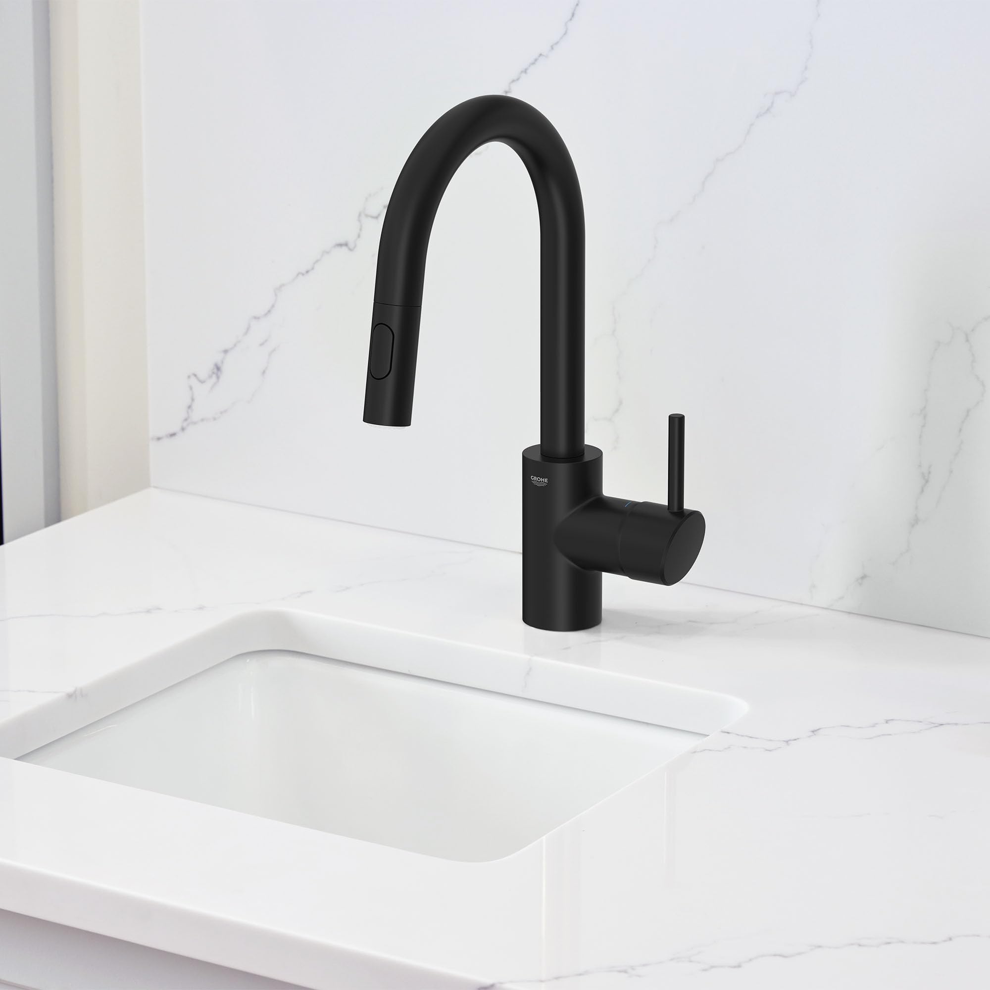 Matte black single-handle pull-down bar faucet with curved spout mounted above white sink.