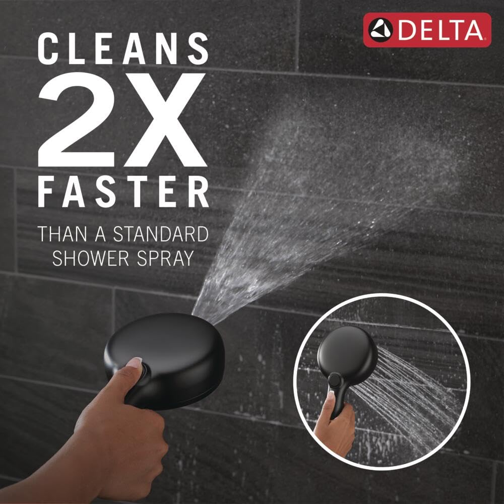 Matte black round hand shower head with cleaning spray function held in hand against dark tile background.