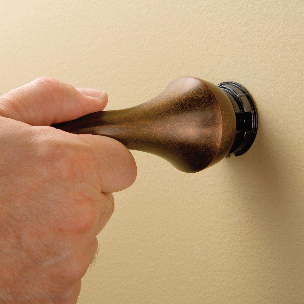 Oil rubbed bronze towel bar with tapered design and black mounting bracket, held in hand against beige wall.