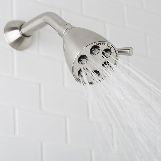 Brushed nickel shower head with multiple spray jets and adjustable arm mounted on white tile wall.