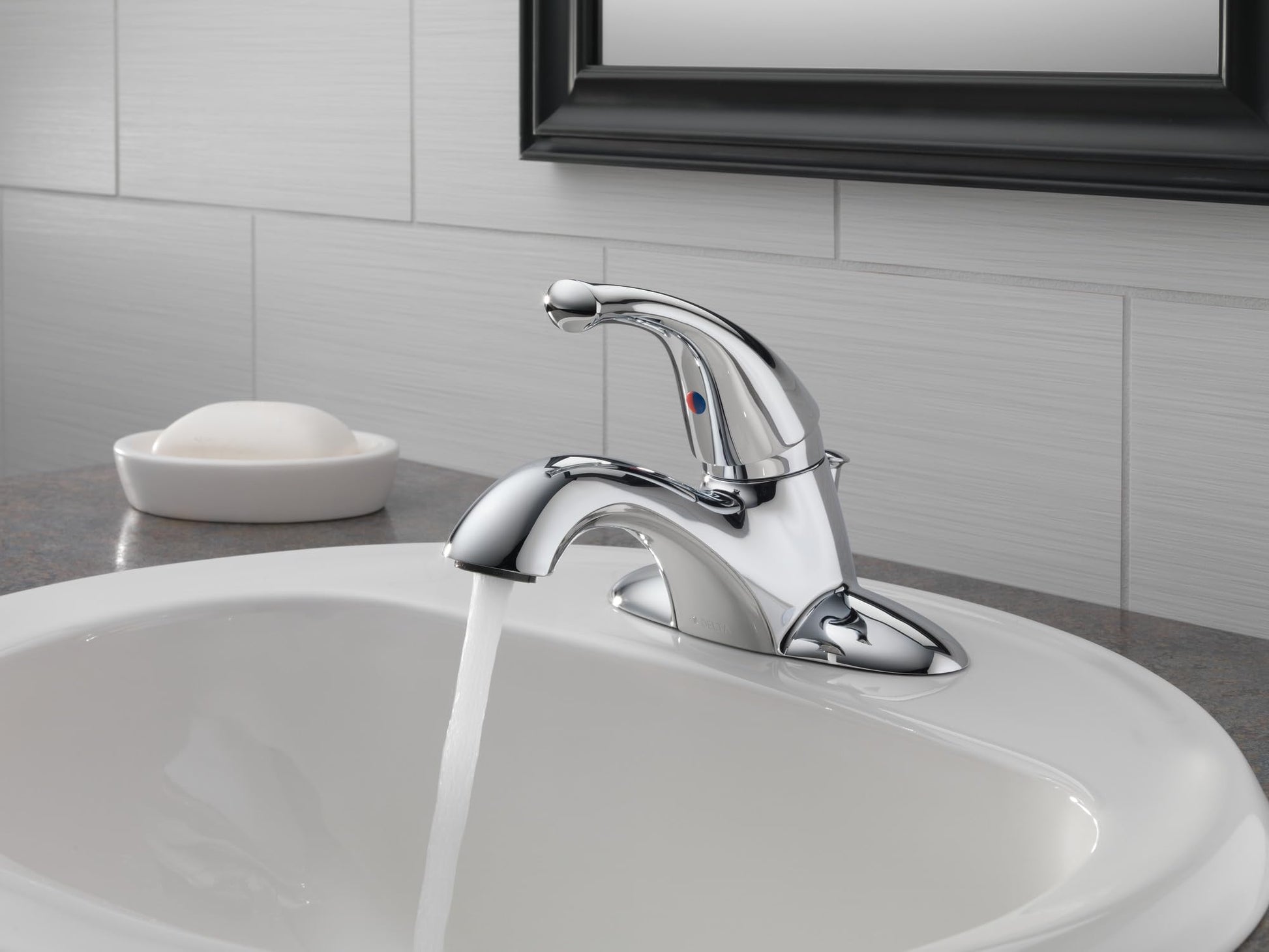 Chrome single-handle bathroom faucet with curved spout mounted on white sink with water running.