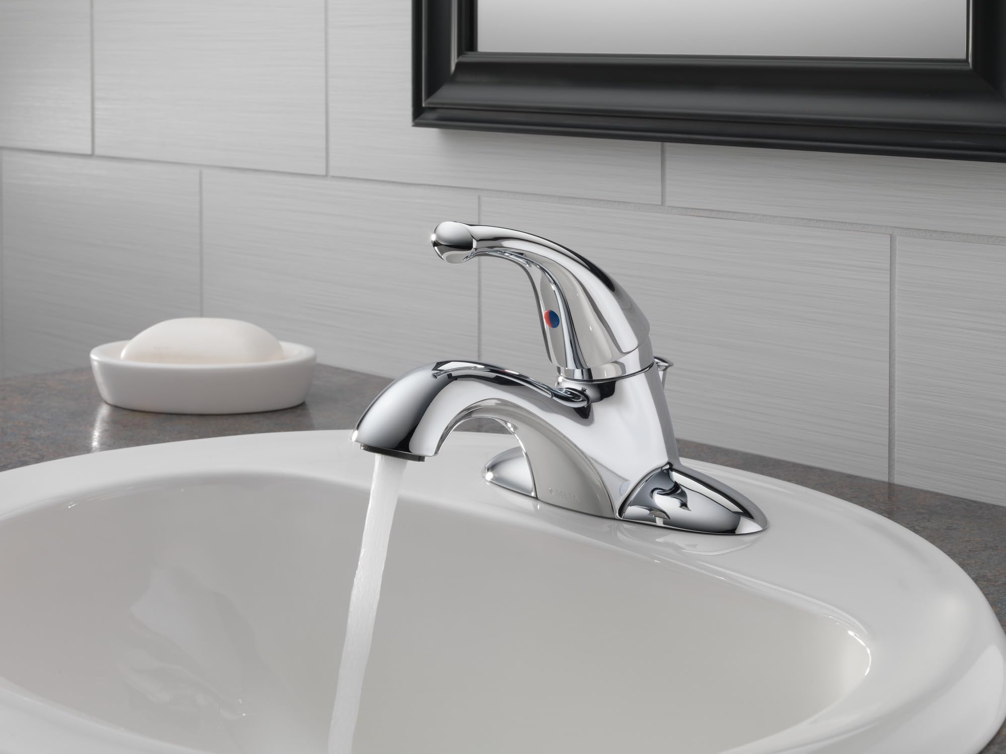 Chrome single-handle bathroom faucet with curved spout mounted on white sink with water running.