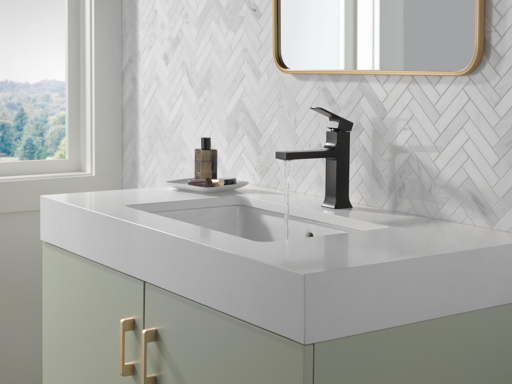 Matte black single-handle bathroom faucet with tall spout installed on white sink in herringbone tile bathroom.