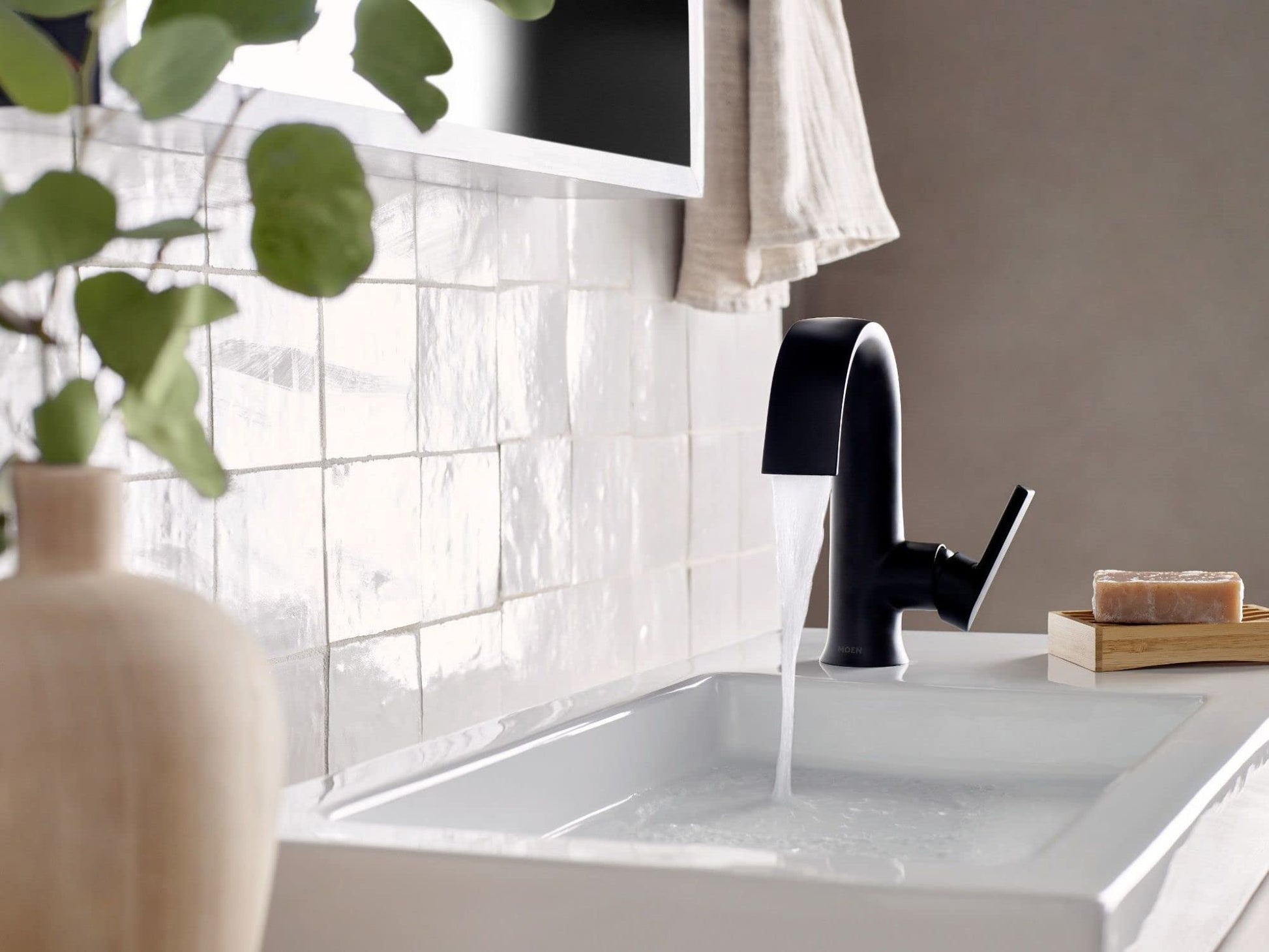 Matte black single-handle bathroom faucet with high arc spout installed on white sink countertop.