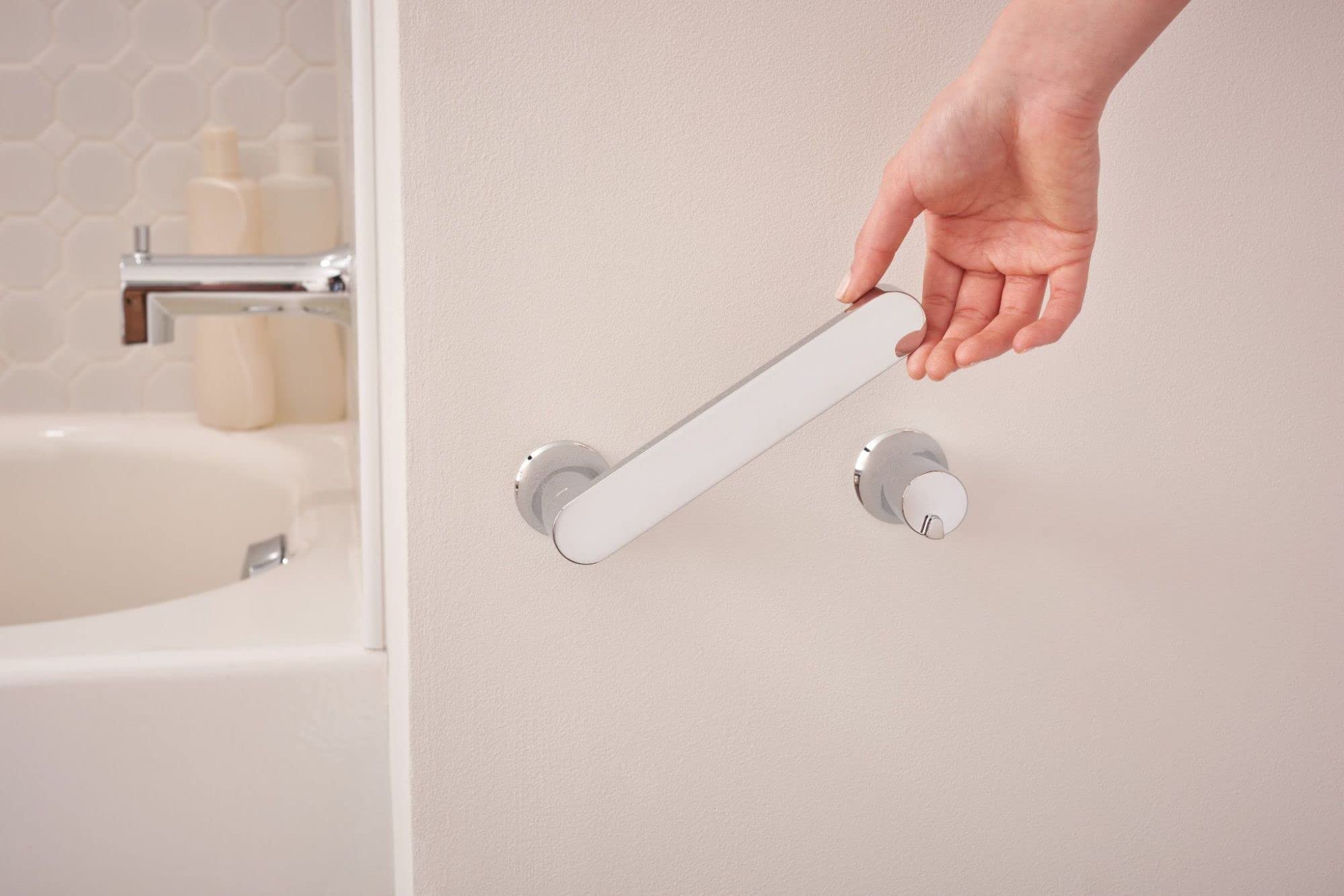 Chrome and white pivoting toilet paper holder mounted on bathroom wall with hand demonstrating rotating arm mechanism.
