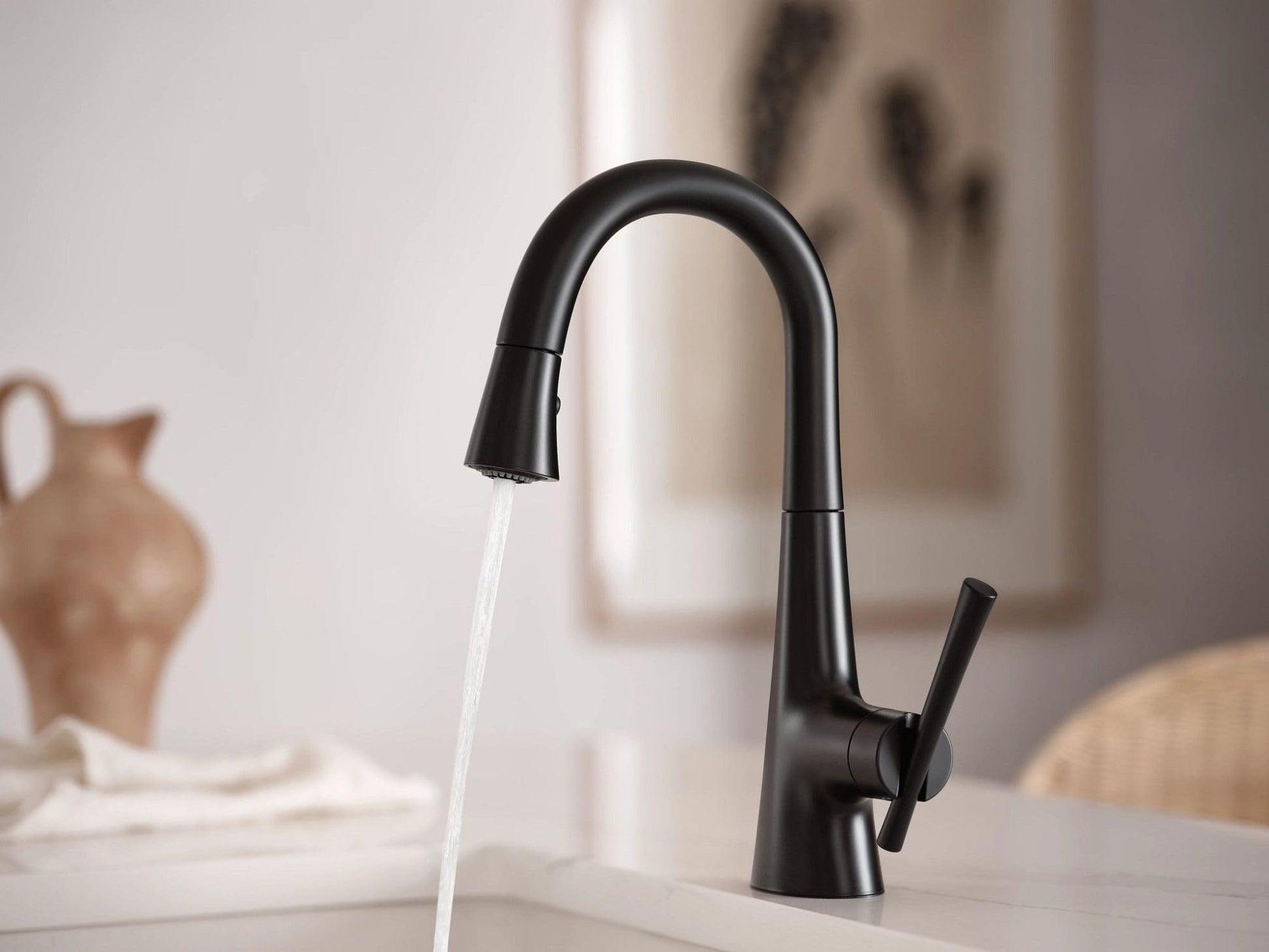 Matte black single-handle pulldown bar faucet with curved spout and lever handle, dispensing water.