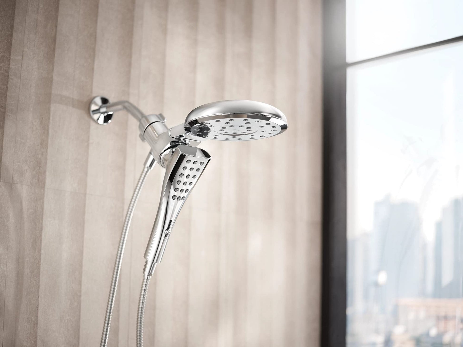Chrome dual shower head with fixed overhead head and handheld wand on flexible hose mounted to wall.