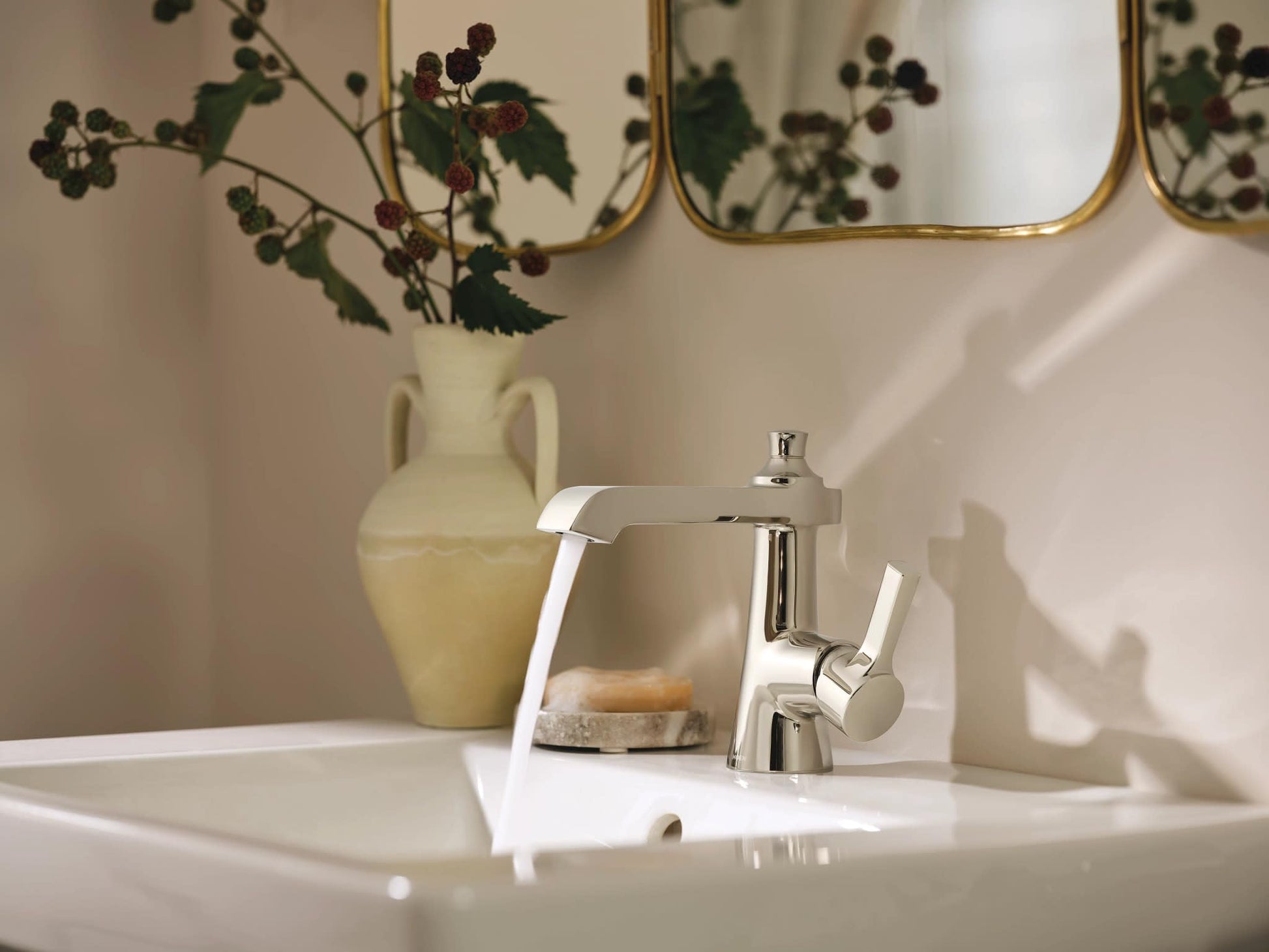 Polished nickel single-handle bathroom faucet with curved spout installed on white sink.